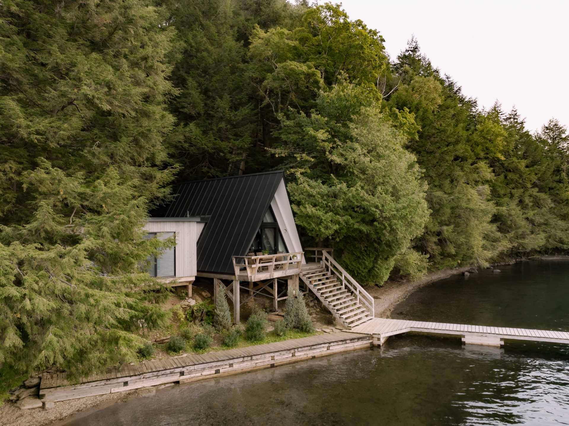 Natural white cedar, metal roofing and modern windows give this classic A-frame cabin a durable new exterior while preserving its iconic shape. A beautiful example of modern cabin renovation.