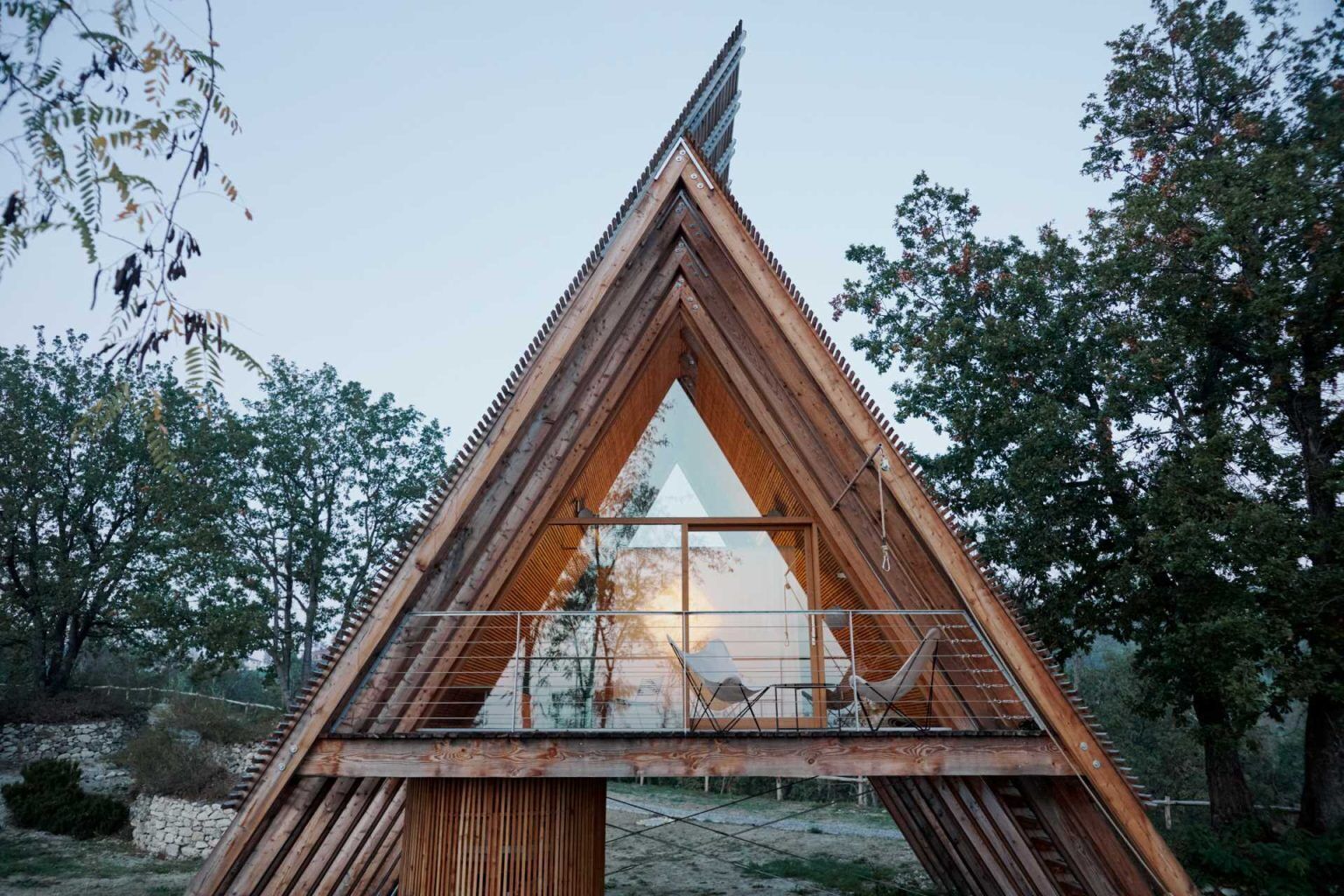 Inspired by traditional haystacks, these contemporary timber cabins combine an A-shaped structure, floor-to-ceiling glazing, and prefabricated construction to create a striking eco-hotel in Italy.