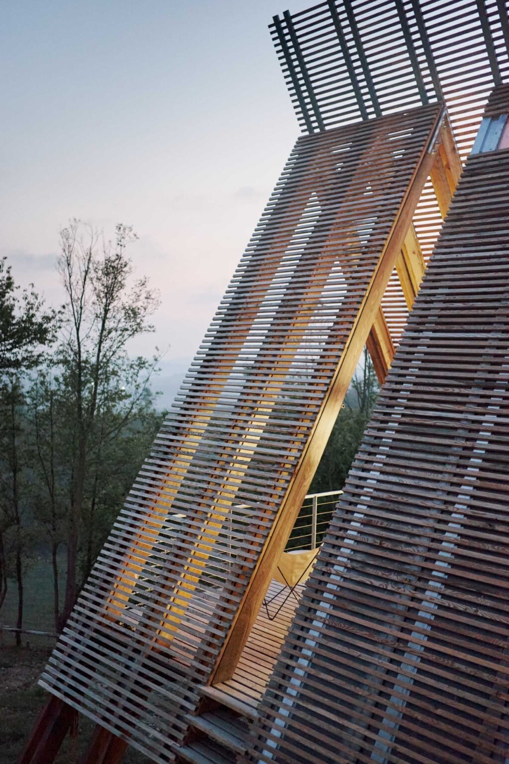 Inspired by traditional haystacks, these contemporary timber cabins combine an A-shaped structure, floor-to-ceiling glazing, and prefabricated construction to create a striking eco-hotel in Italy.