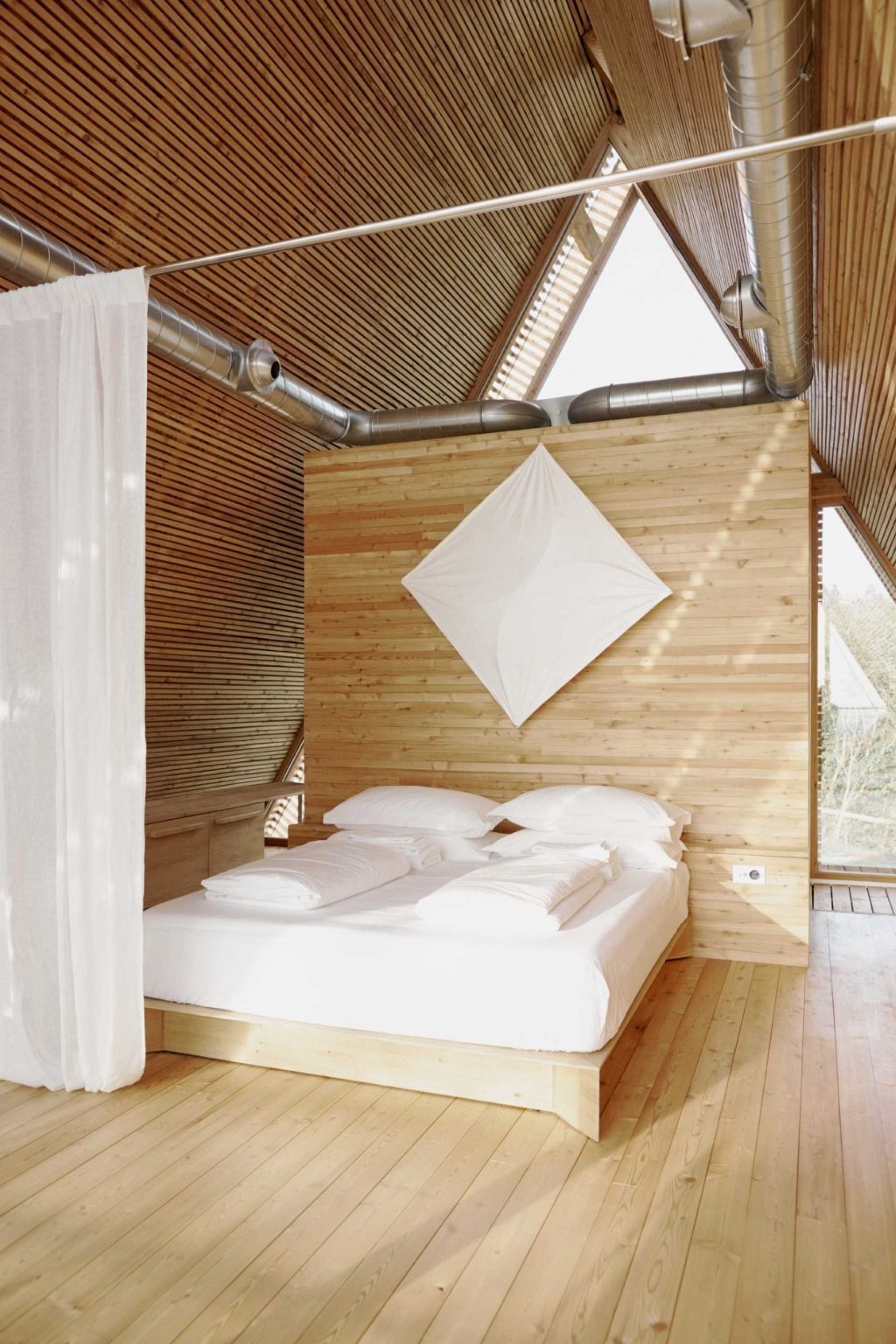 Floor-to-ceiling curtains offer a simple way to create privacy while preserving the open feel of these minimalist timber cabins.