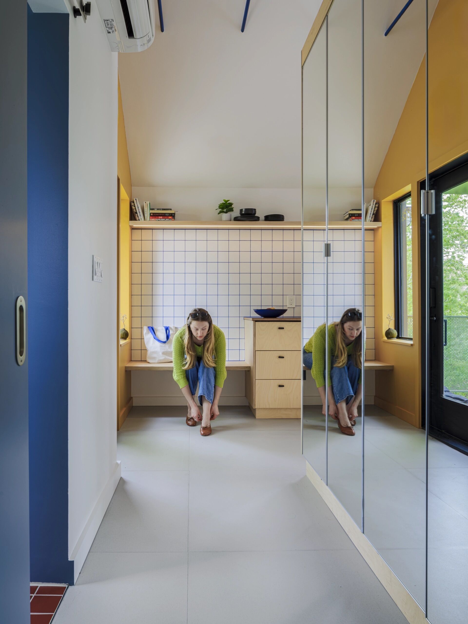 A built-in bench creates a practical welcome while introducing the clever layout hidden inside this compact apartment.