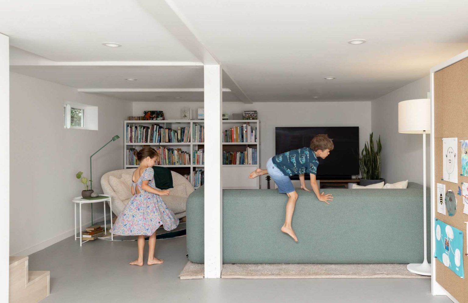 This once-dark basement now serves as a bright playroom, family lounge, guest room, and storage area all in one flexible space.