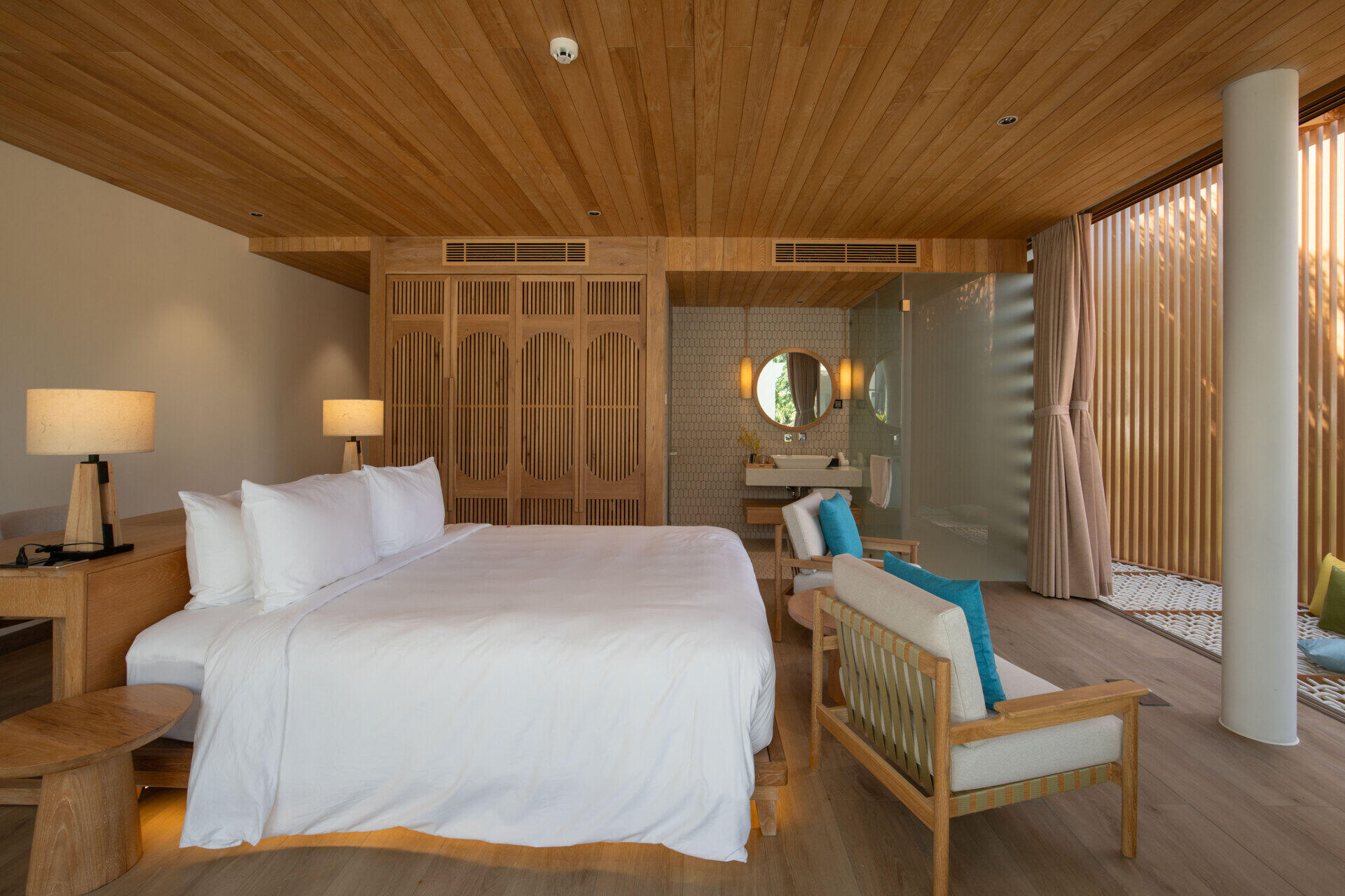 Warm timber finishes, a round soaking tub and a woven lounge net create a resort-inspired guest bedroom designed for relaxed coastal living.