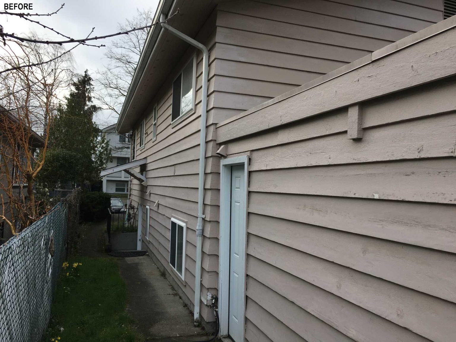 BEFORE - A colorful new front entry, warm wood siding, larger windows, and a welcoming façade completely change the street presence of this renovated Seattle home.