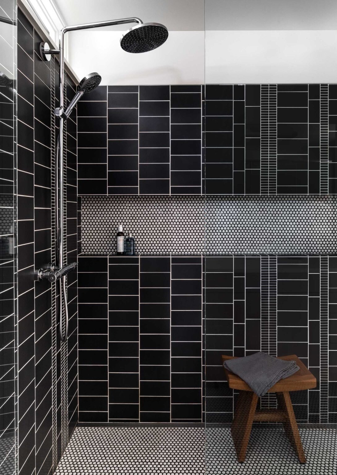 Black wall tiles, white penny tiles, and contrasting grout give this modern bathroom plenty of character.