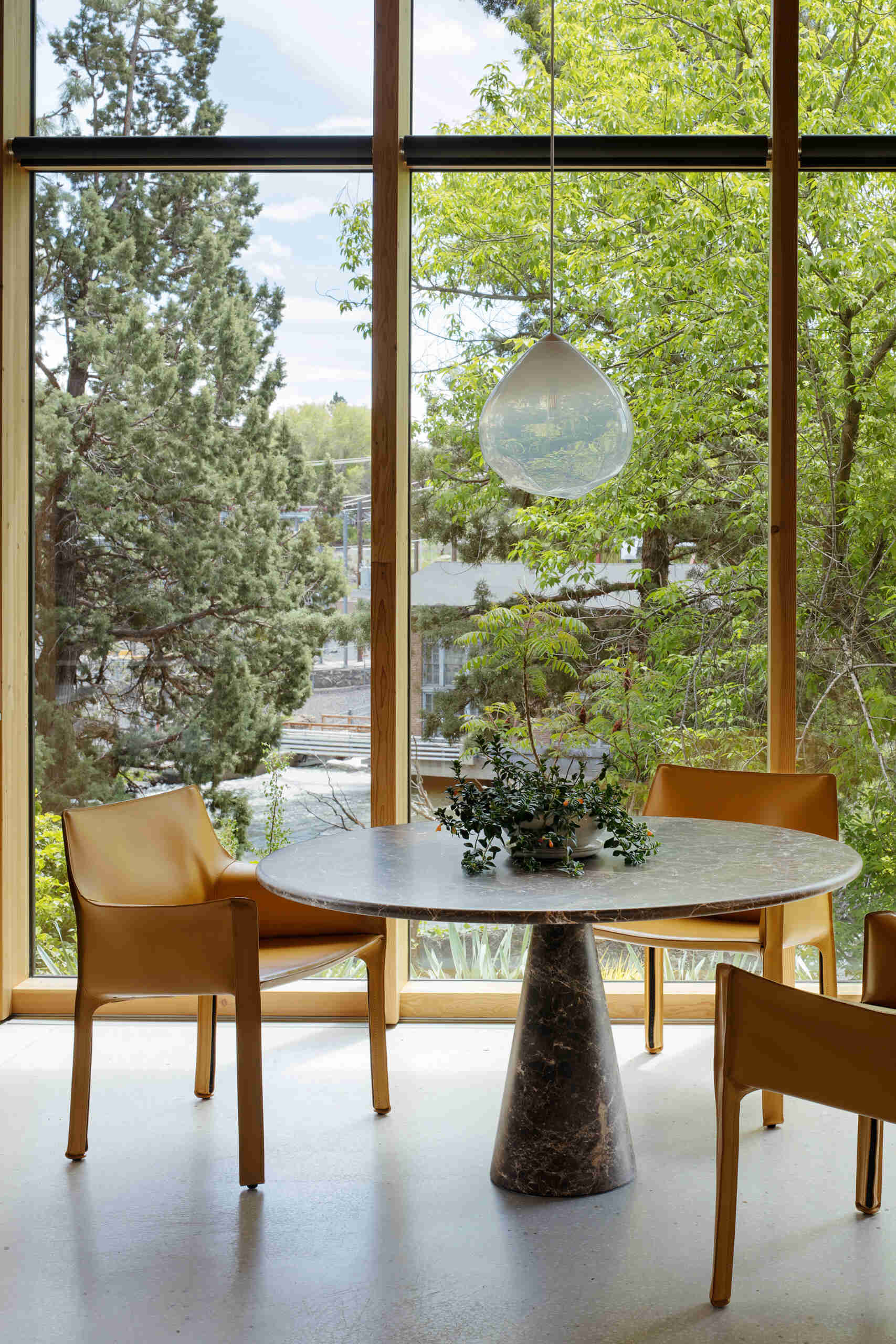 Visite la cocina moderna y luminosa con cálidos gabinetes de madera, una isla blanca y un tranquilo rincón para desayunar con vista a los árboles circundantes.