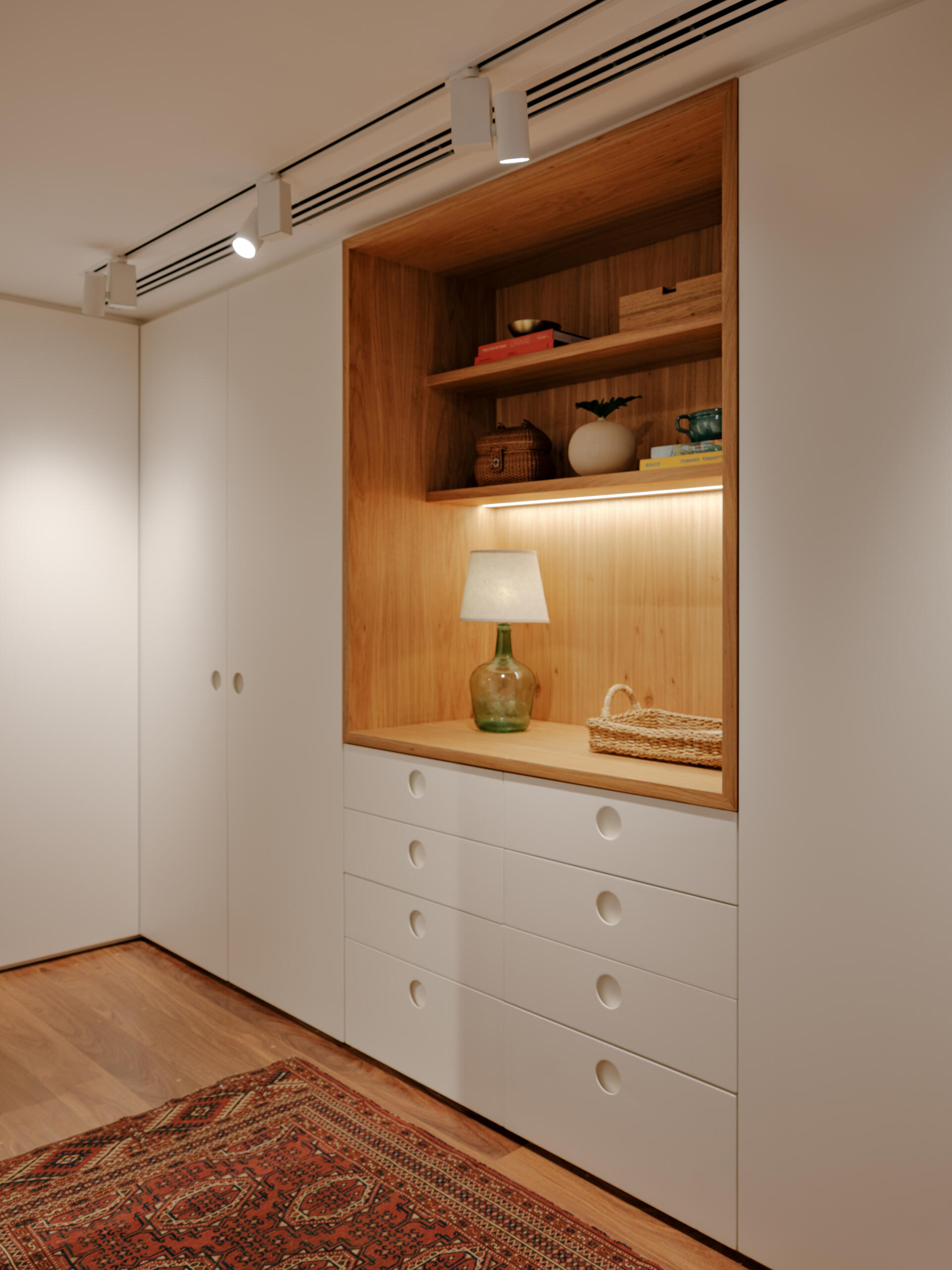 Custom wardrobes with illuminated timber niches turn a simple hallway into a beautiful design feature.