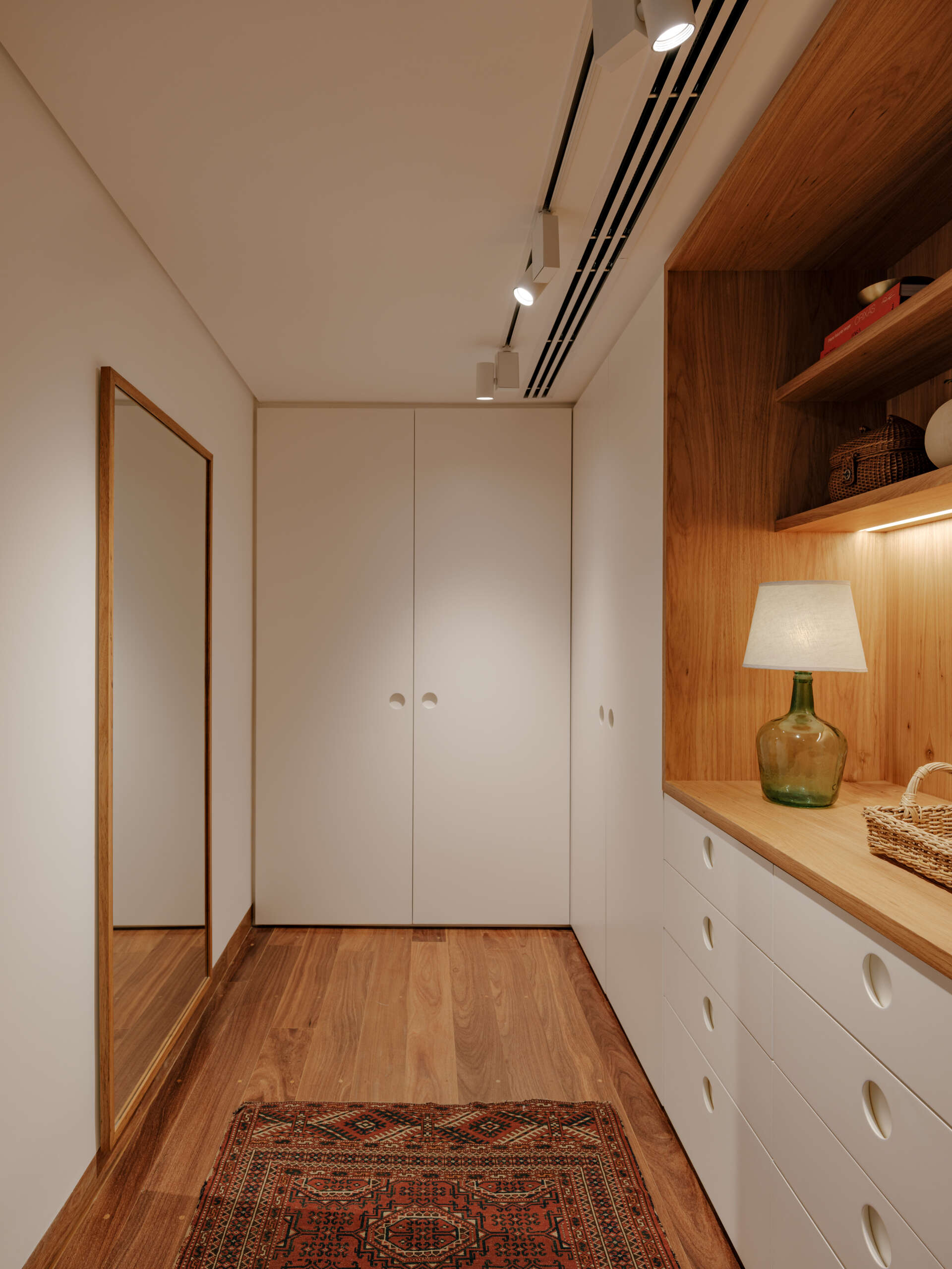 Custom wardrobes with illuminated timber niches turn a simple hallway into a beautiful design feature.