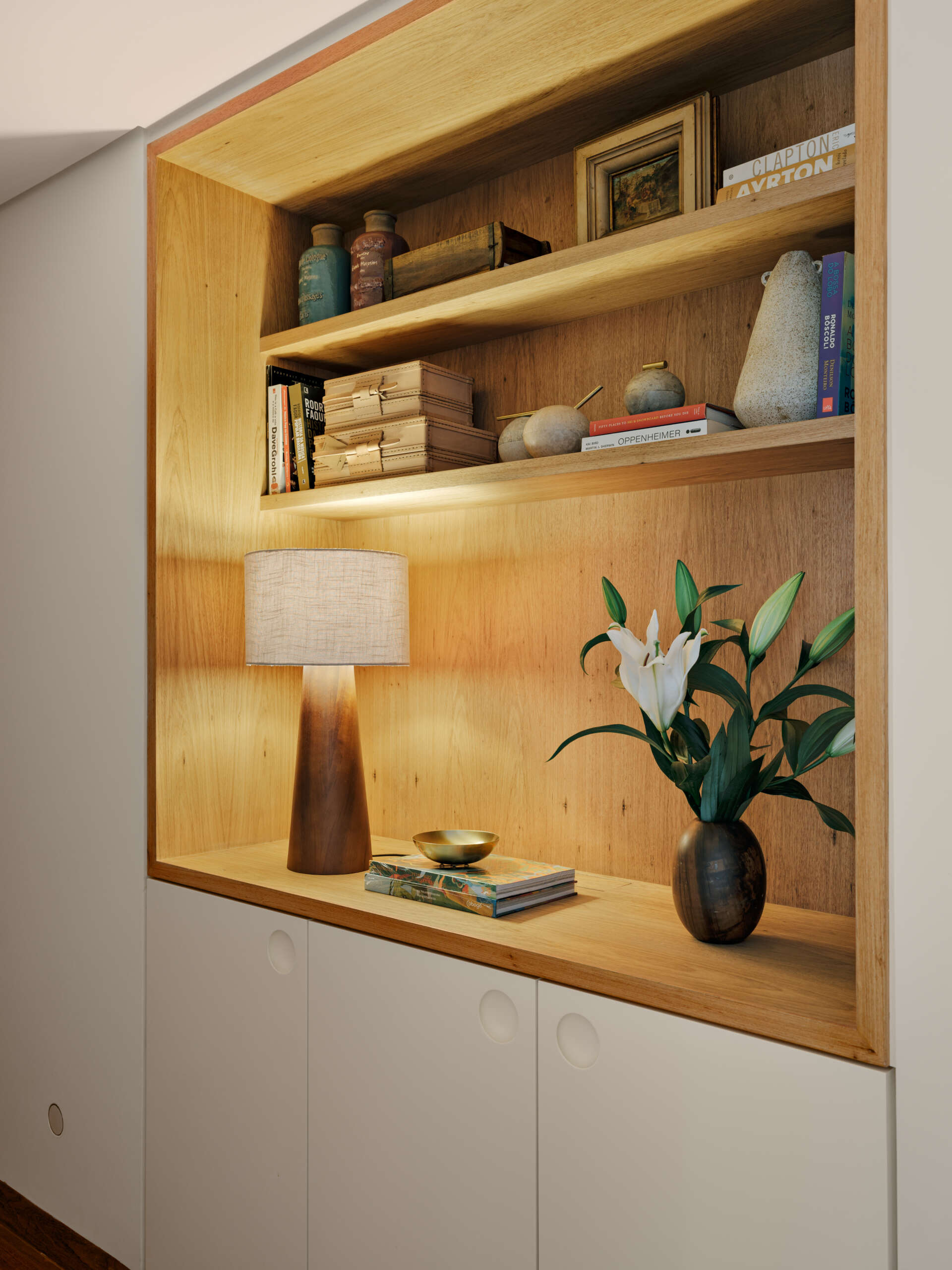 Custom wardrobes with illuminated timber niches turn a simple hallway into a beautiful design feature.