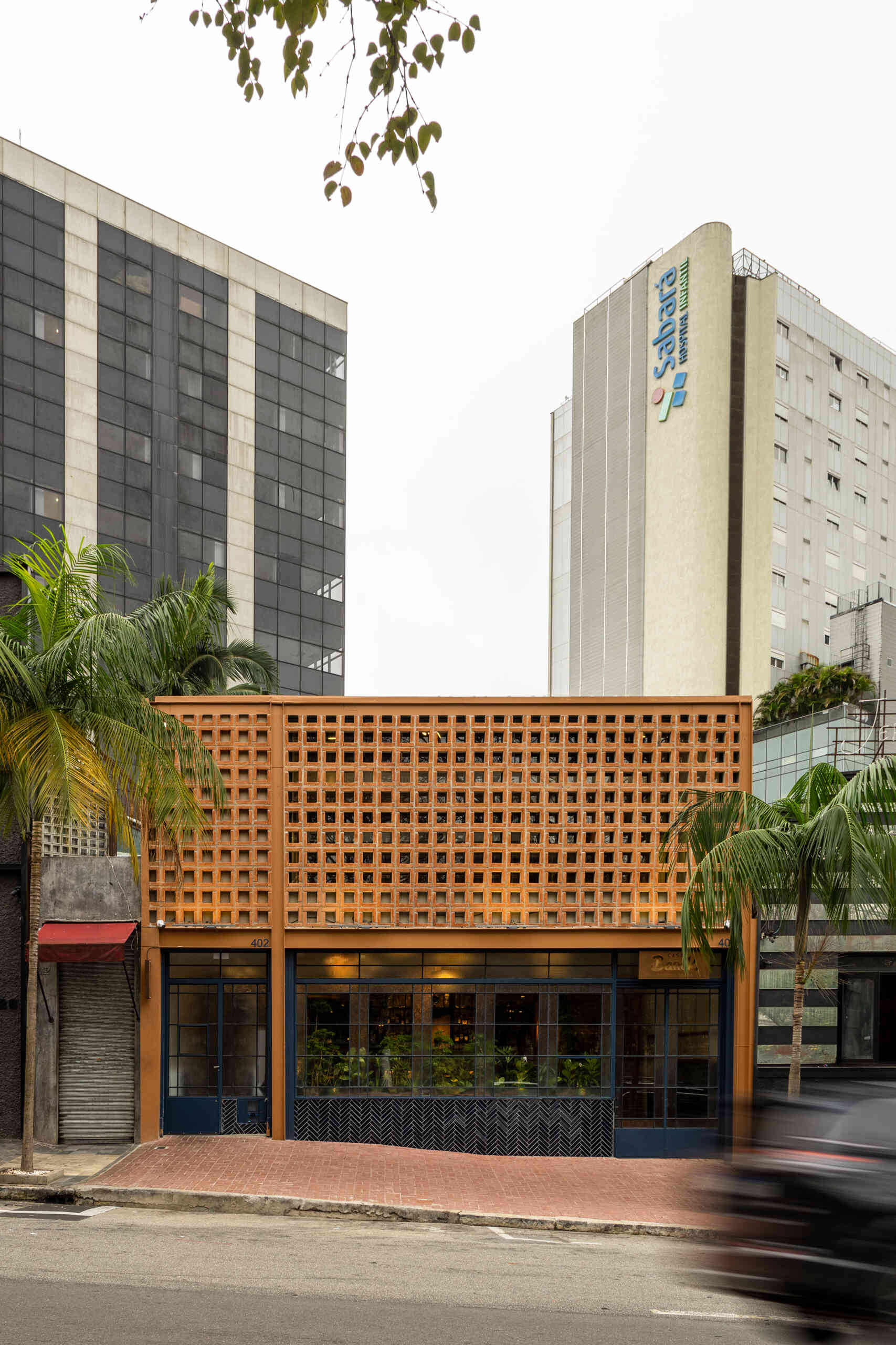 Casa Baruk’s façade combines a terracotta steel frame, blue ironwork, and a ceramic mashrabiya-inspired screen that filters light and creates privacy while maintaining a visual connection with the street.