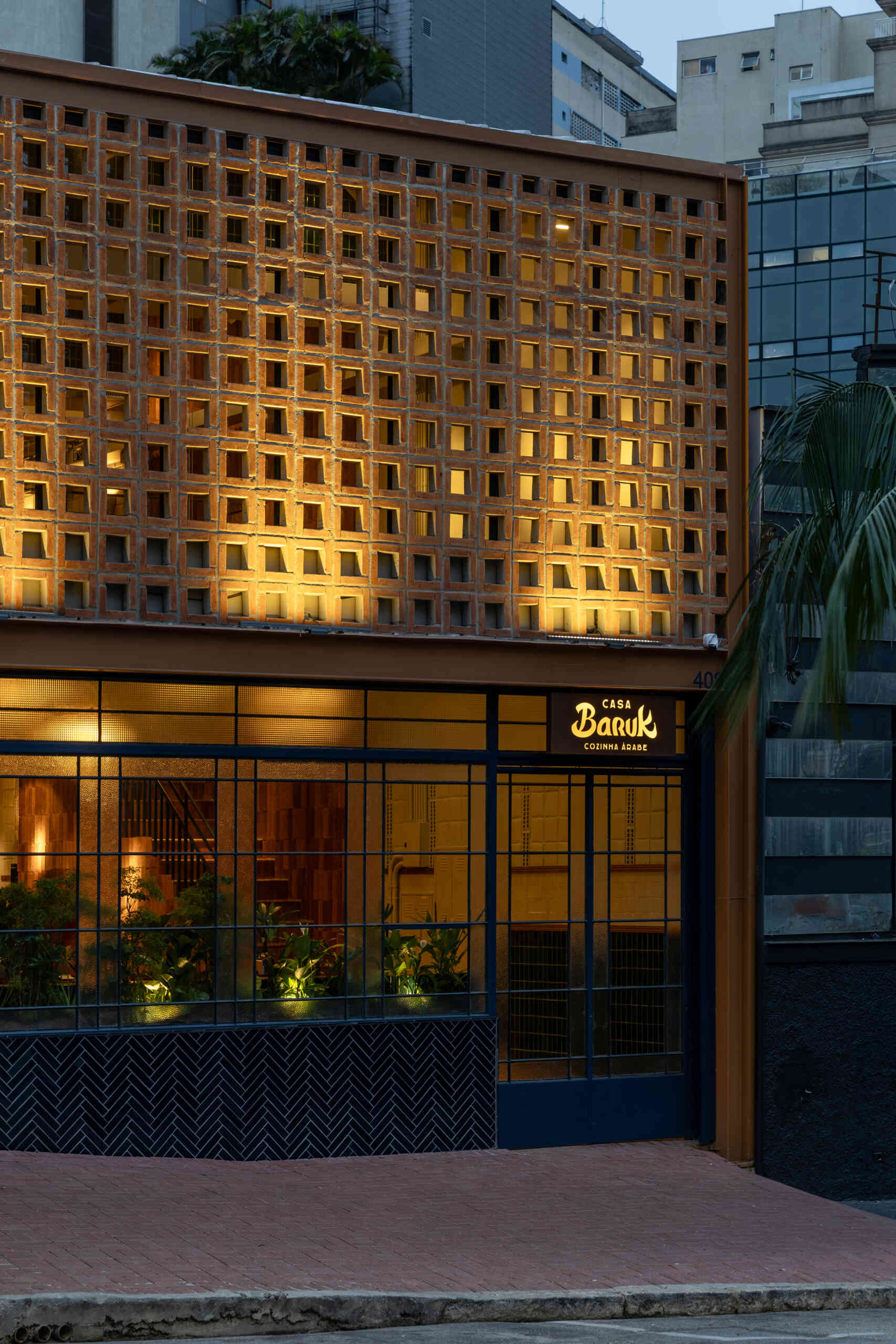 Casa Baruk’s façade combines a terracotta steel frame, blue ironwork, and a ceramic mashrabiya-inspired screen that filters light and creates privacy while maintaining a visual connection with the street.