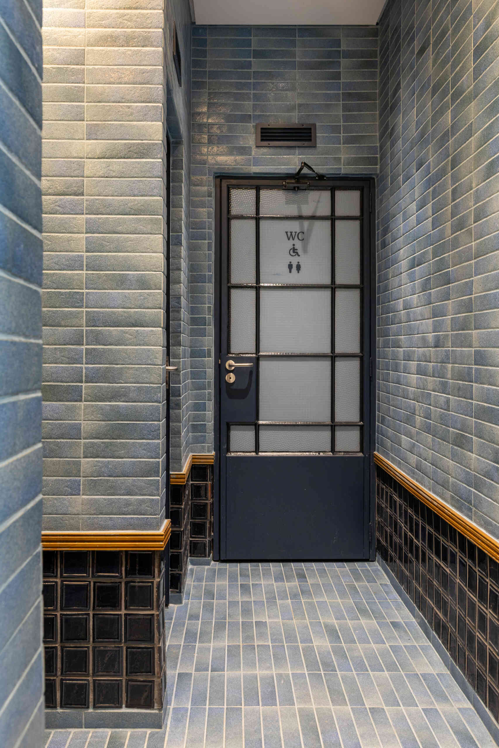 Blue and green ceramic tile panels, vintage mirrors, wooden detailing, and concrete sinks give the bathrooms the same architectural quality and material richness found throughout Casa Baruk.