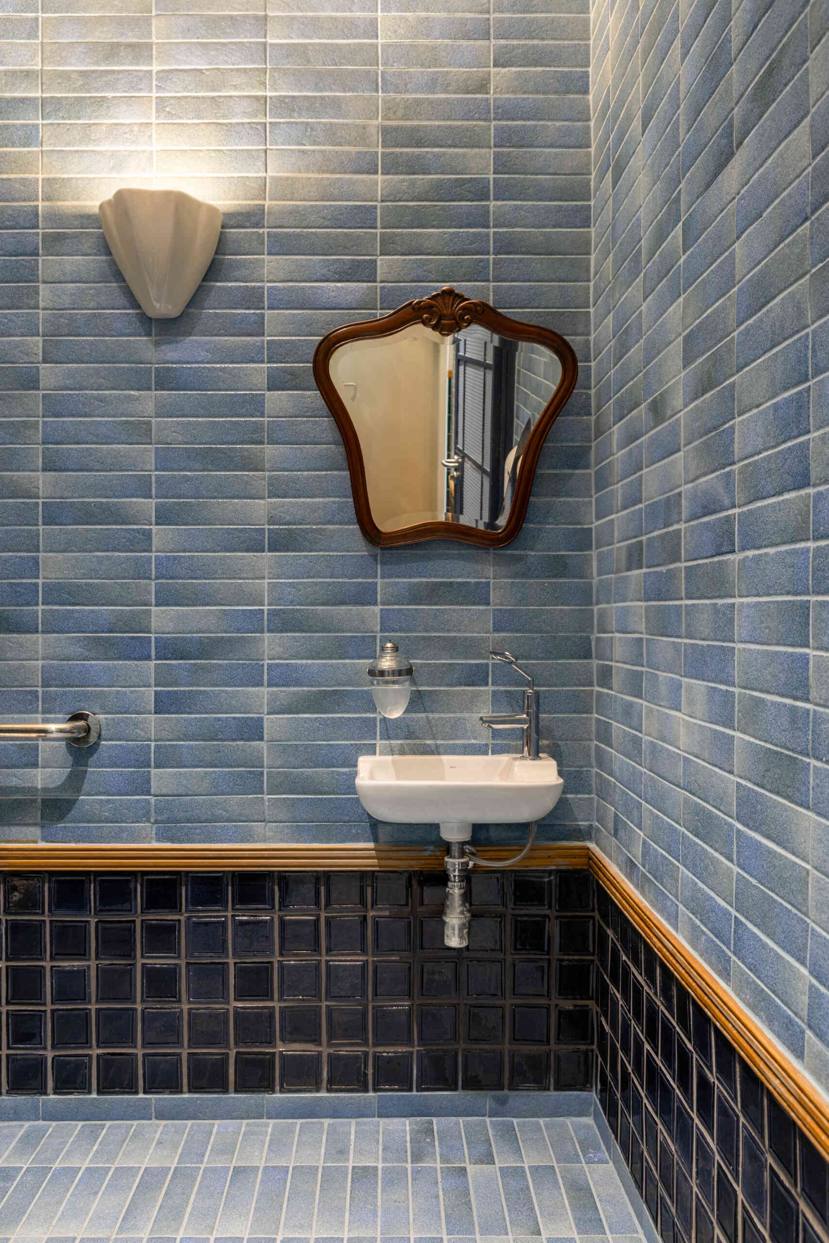 Blue and green ceramic tile panels, vintage mirrors, wooden detailing, and concrete sinks give the bathrooms the same architectural quality and material richness found throughout Casa Baruk.