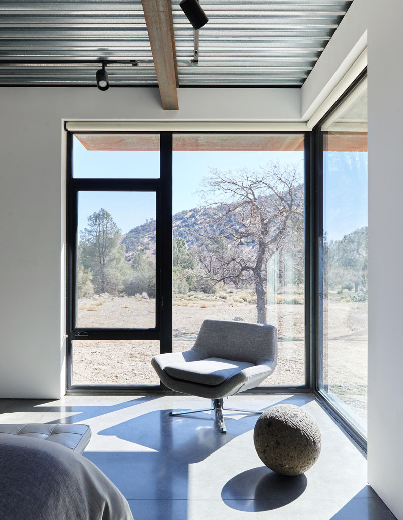 Floor-to-ceiling corner windows frame sweeping views across California's rugged desert landscape.