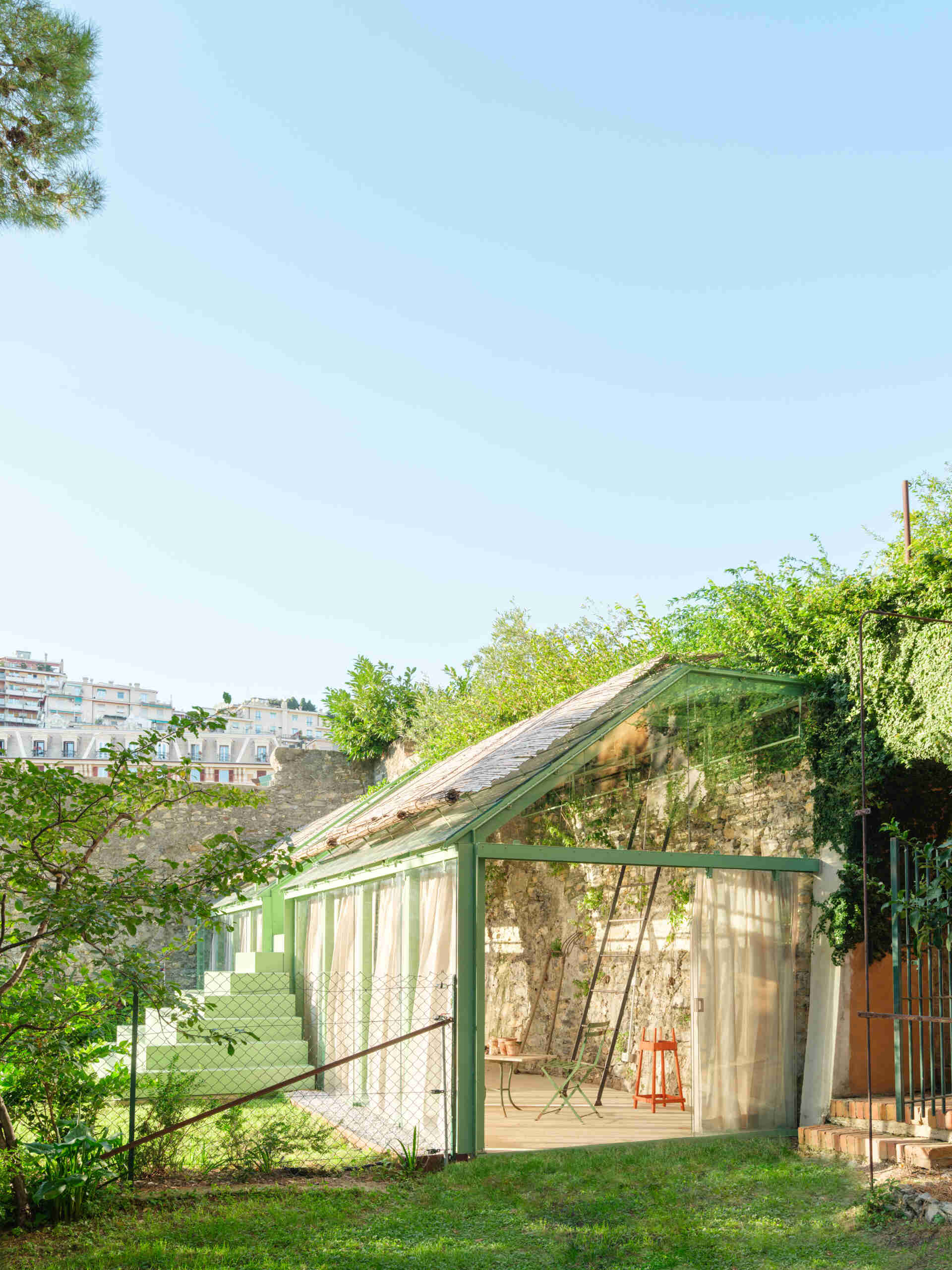 See how a transparent greenhouse filled with natural light creates a seamless visual connection with the surrounding garden.