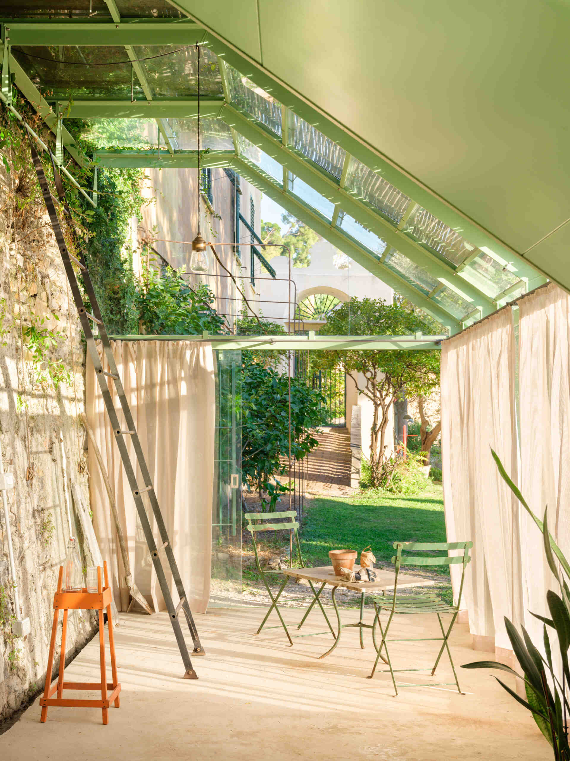 See how a transparent greenhouse filled with natural light creates a seamless visual connection with the surrounding garden.