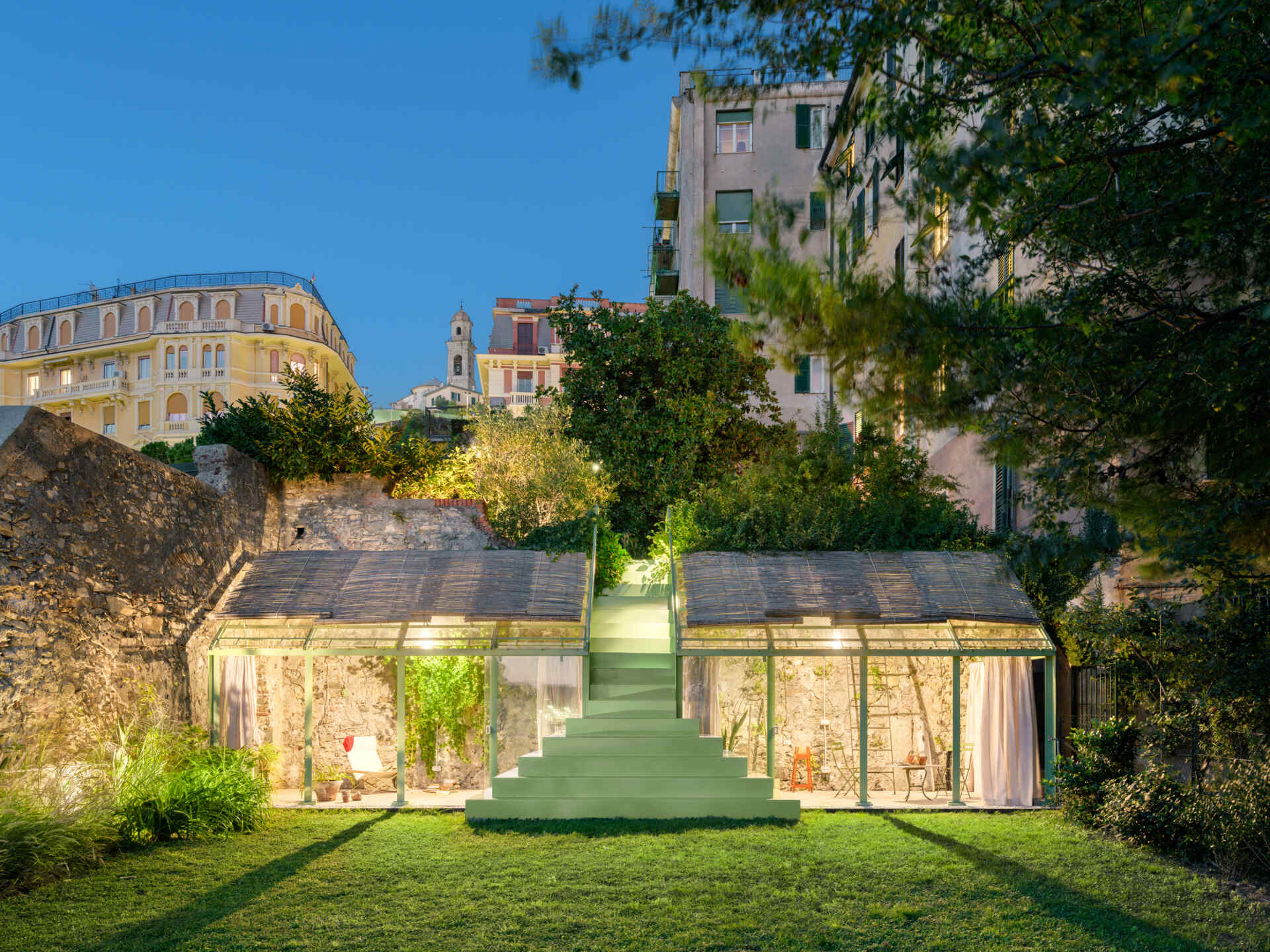See how soft evening lighting transforms this sculptural staircase and glass greenhouse into a glowing garden feature after sunset.