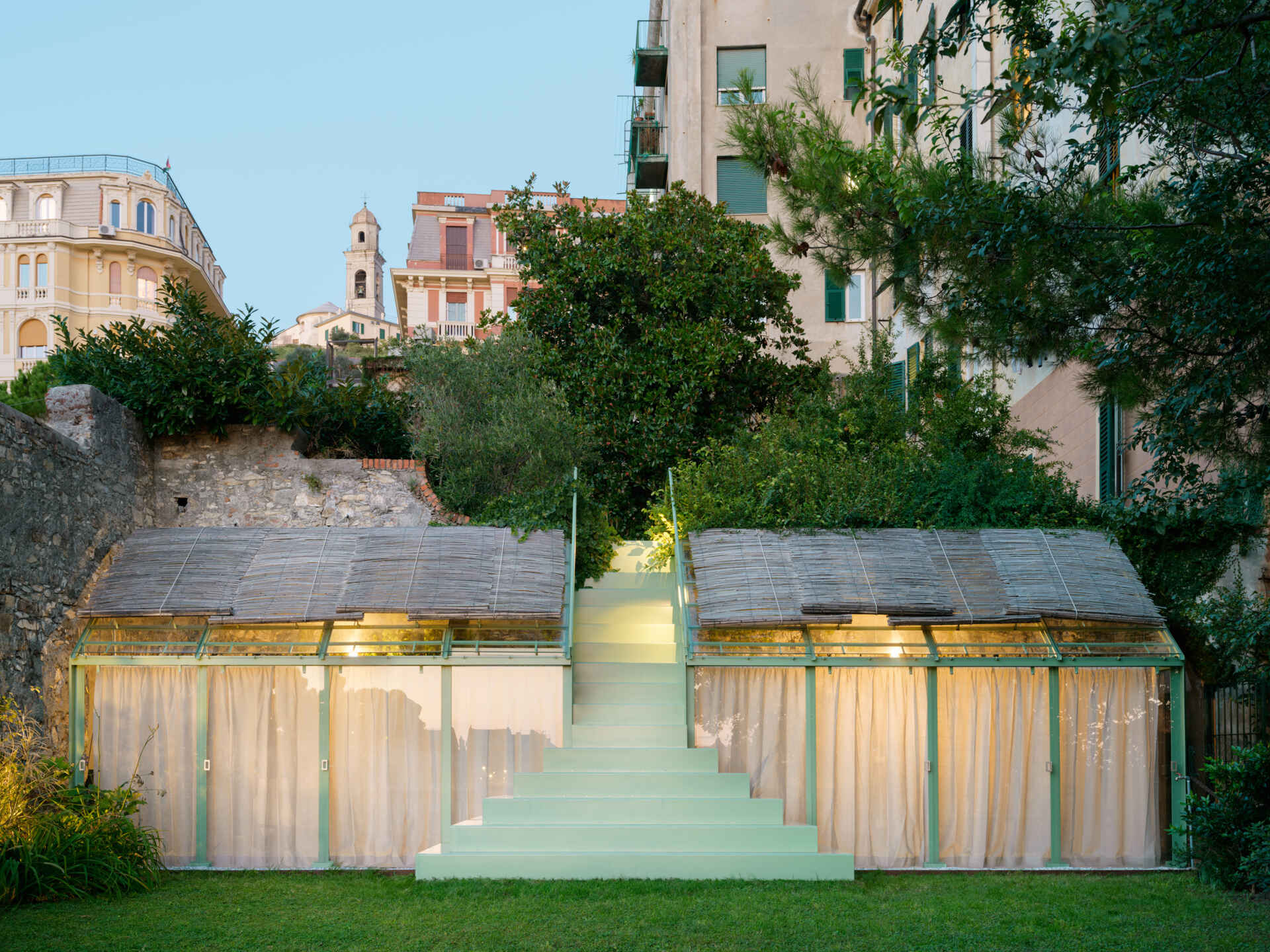 See how soft evening lighting transforms this sculptural staircase and glass greenhouse into a glowing garden feature after sunset.