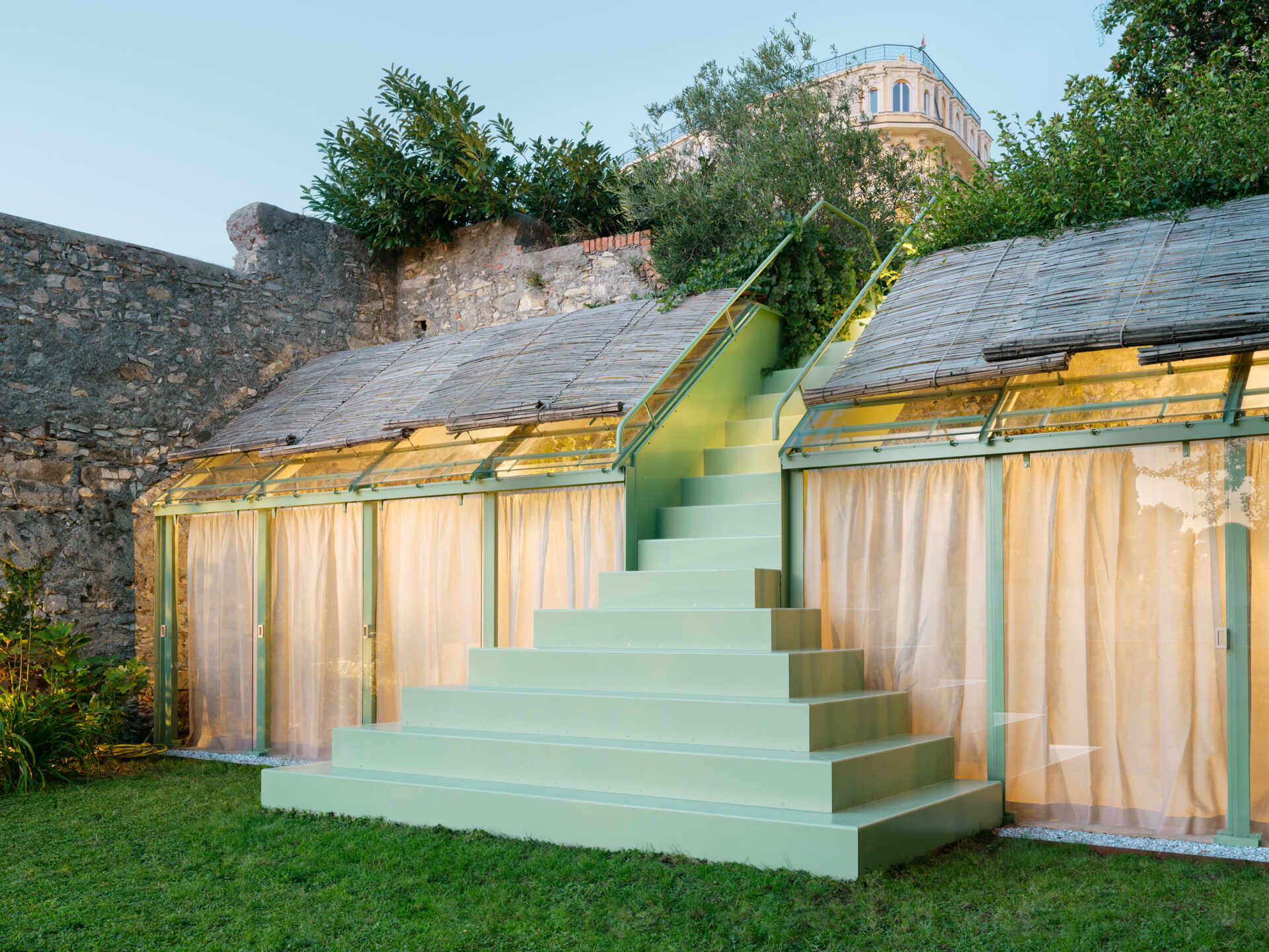 See how soft evening lighting transforms this sculptural staircase and glass greenhouse into a glowing garden feature after sunset.