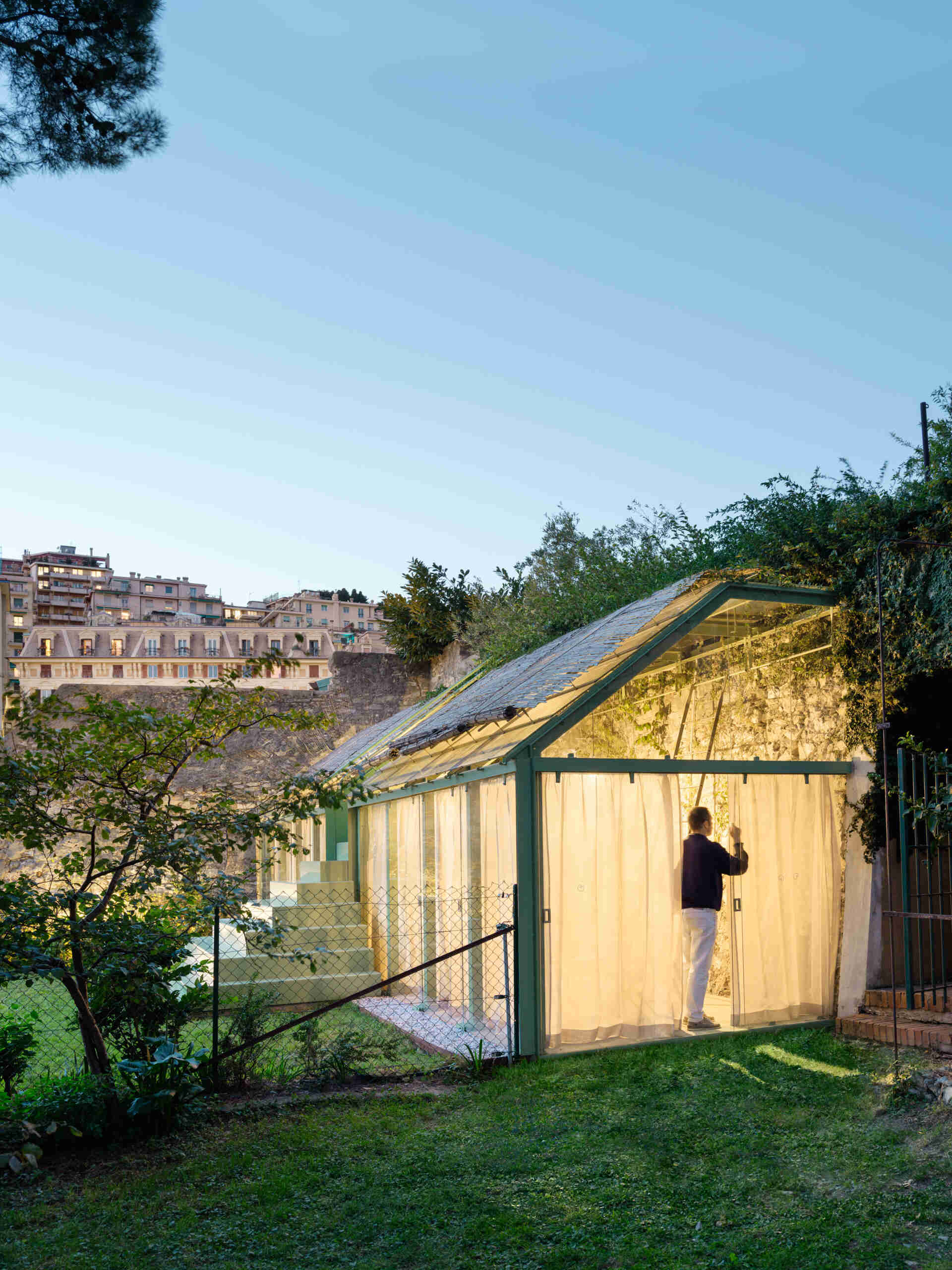 See how soft evening lighting transforms this sculptural staircase and glass greenhouse into a glowing garden feature after sunset.