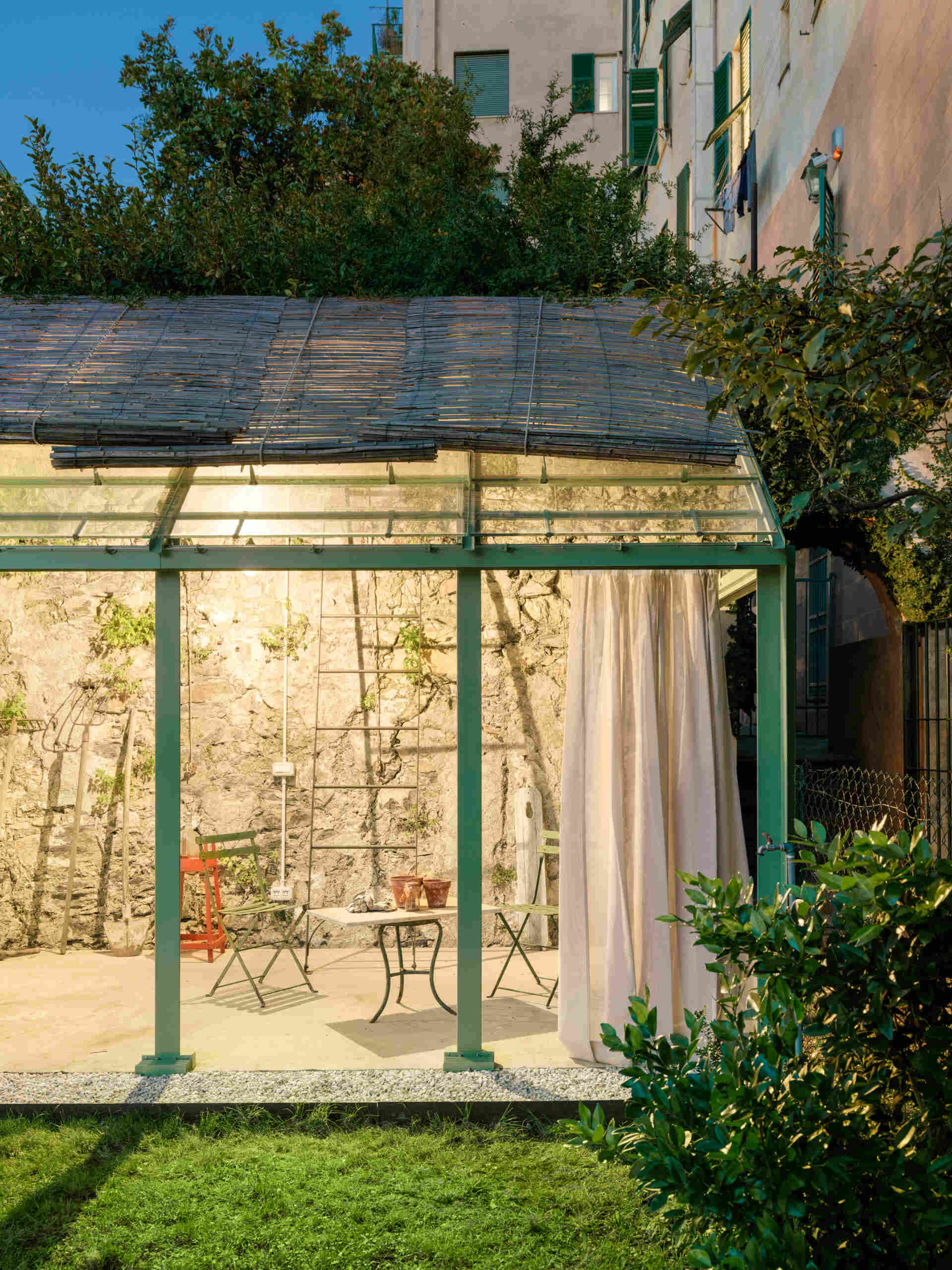 See how soft evening lighting transforms this sculptural staircase and glass greenhouse into a glowing garden feature after sunset.