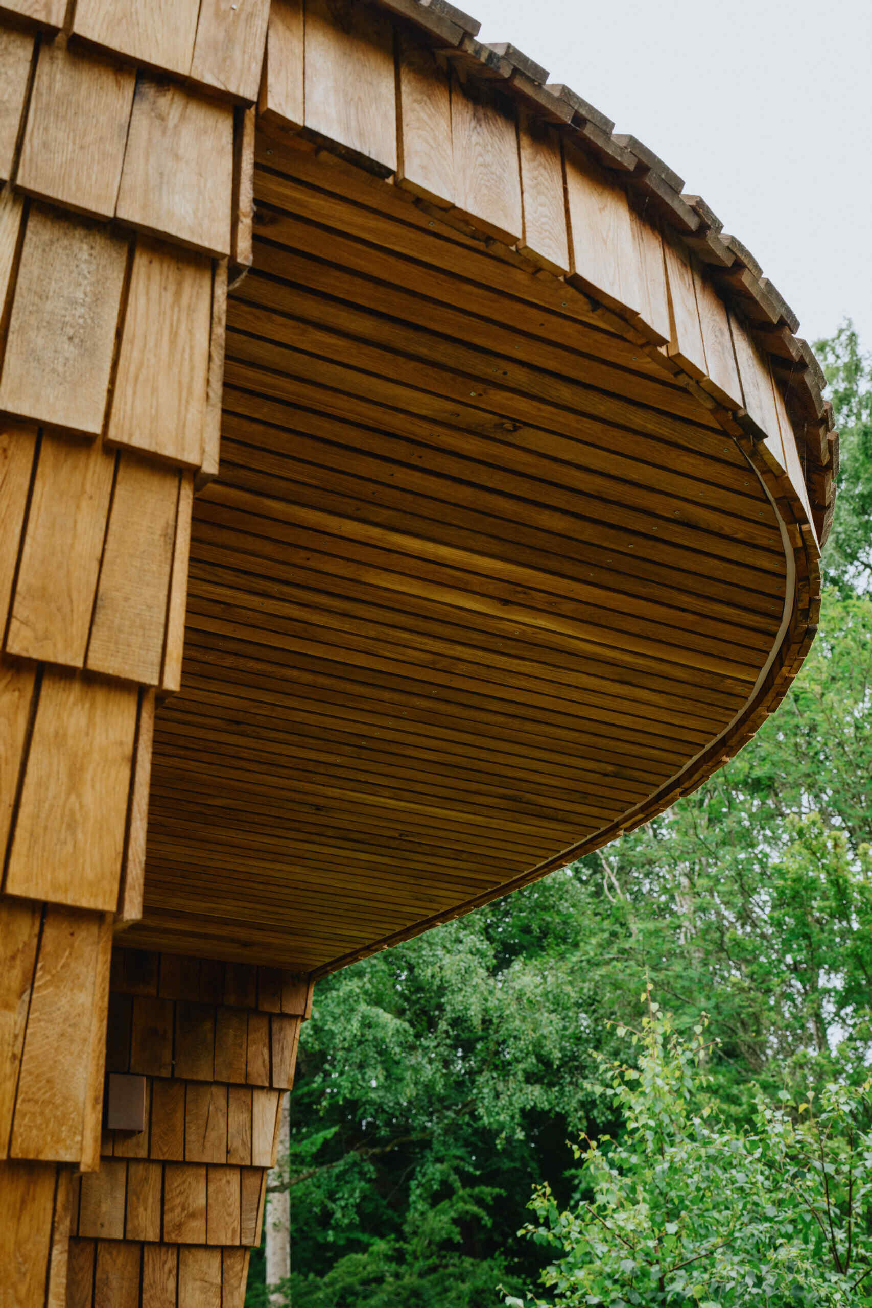 Natural timber, digital fabrication, and a low-carbon approach shape a garden house's warm exterior and efficient construction.