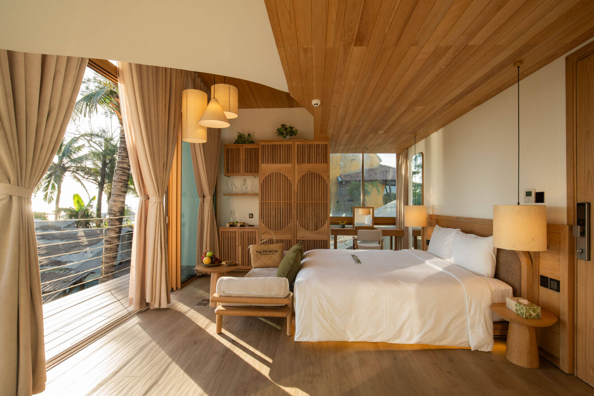 Sun-filled interiors, warm timber finishes and balcony views of palms and the water make this guest bedroom a calm coastal escape.
