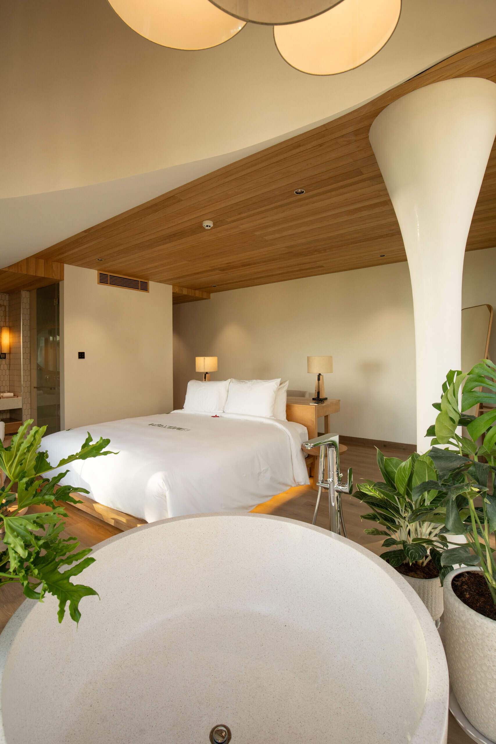 Ocean views, tropical greenery and a round soaking tub give this bright guest bedroom the feel of a boutique beachfront suite.