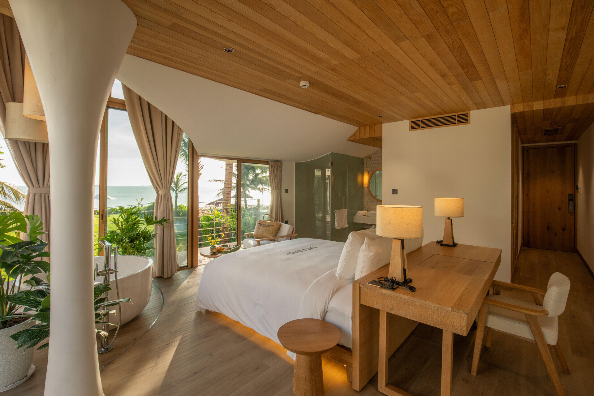 Ocean views, tropical greenery and a round soaking tub give this bright guest bedroom the feel of a boutique beachfront suite.
