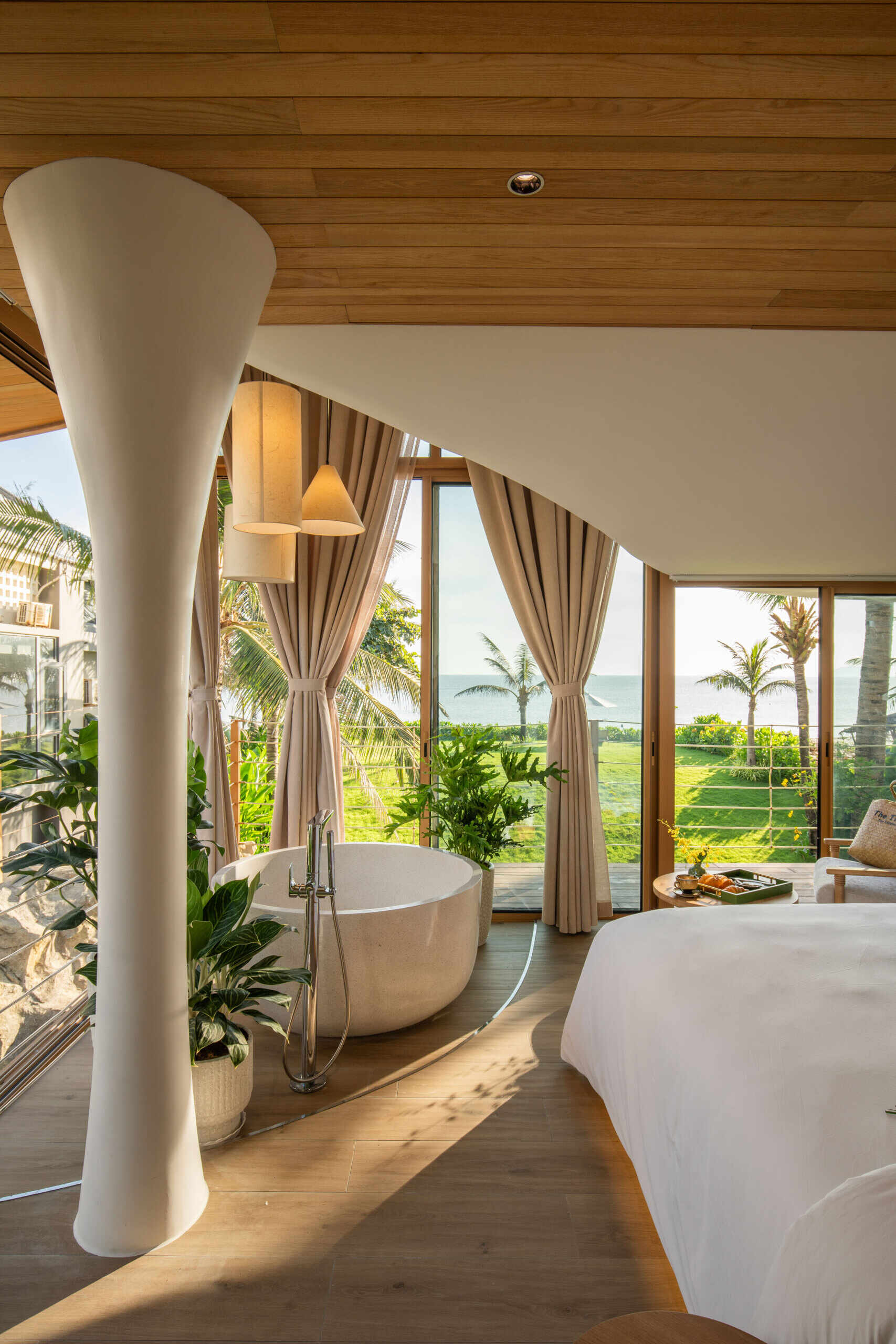Ocean views, tropical greenery and a round soaking tub give this bright guest bedroom the feel of a boutique beachfront suite.