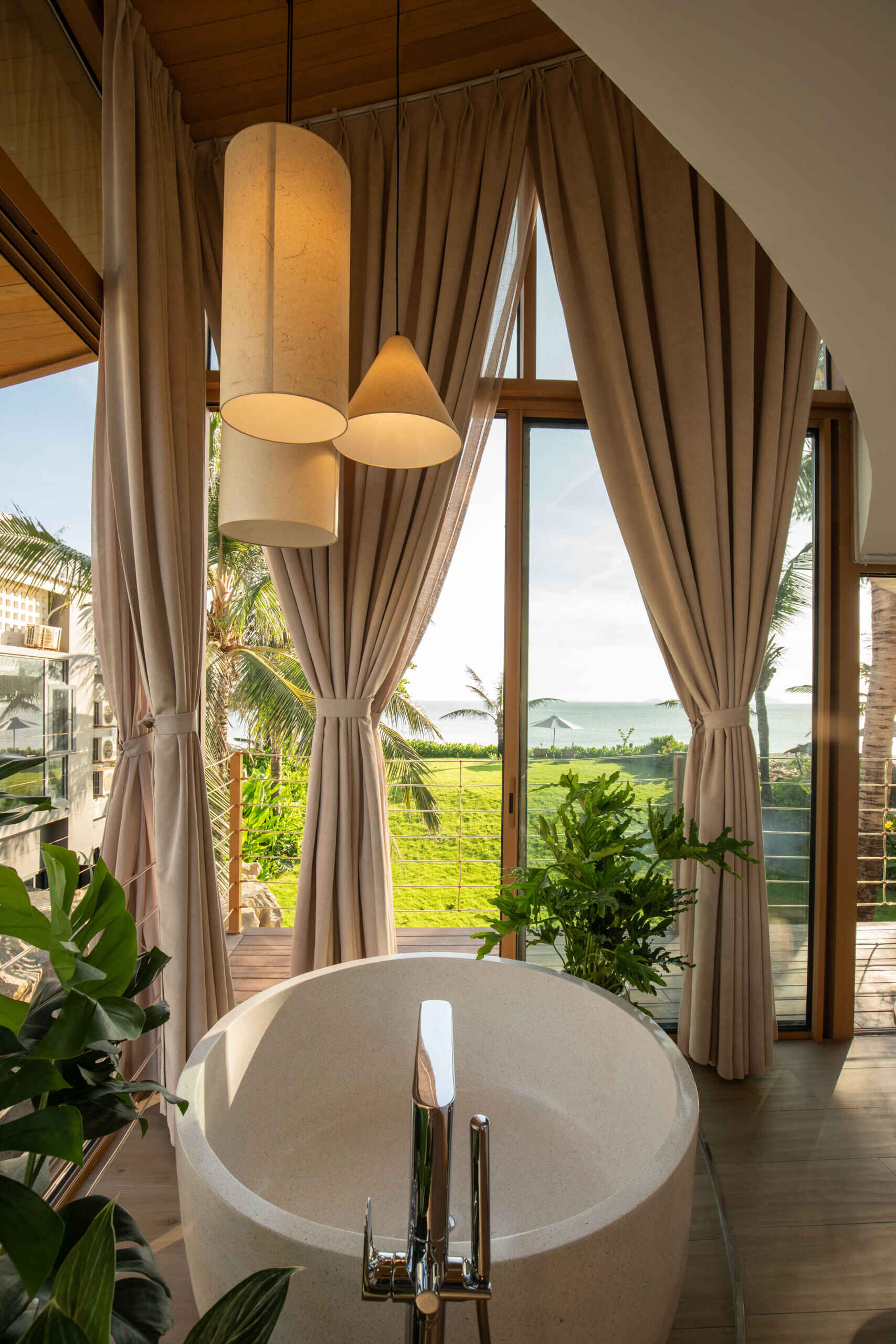 Ocean views, tropical greenery and a round soaking tub give this bright guest bedroom the feel of a boutique beachfront suite.