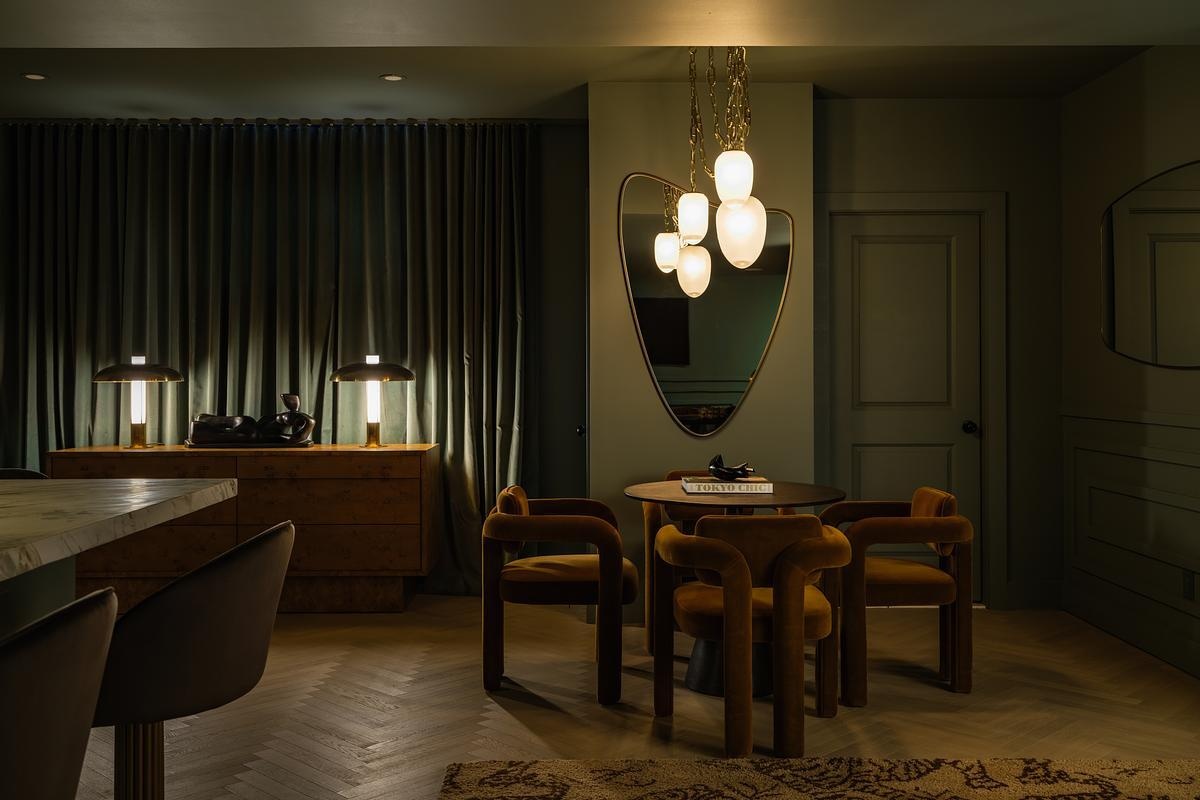This speakeasy-inspired home whiskey lounge features rich green cabinetry, South African marble, brass accents, velvet seating, and vintage-inspired details.