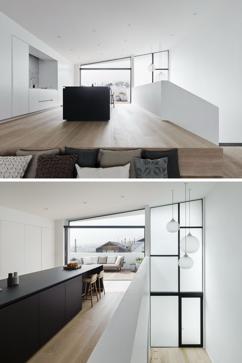 Explore a minimalist kitchen with a bold black island, hidden powder room, timber seating steps, and clever modern details.