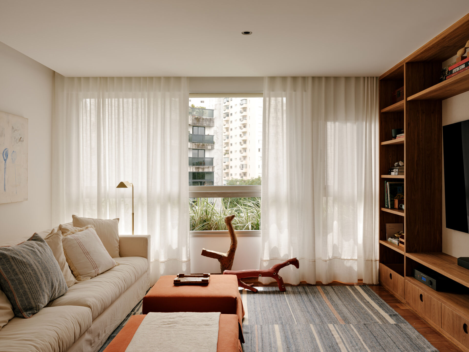 A cosy media room shows how custom shelving, artwork and warm colours can make a TV space feel more inviting.
