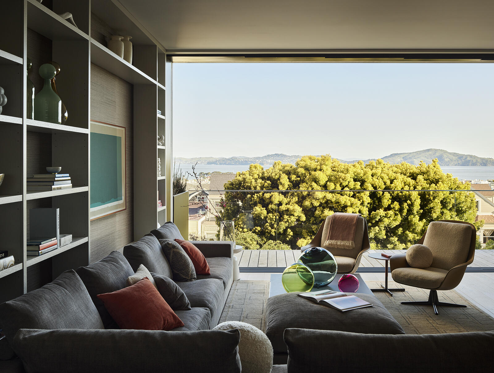 Centered around a custom bookcase filled with travel finds and personal treasures, this welcoming family room blends contemporary design with everyday comfort. A vibrant artwork by Analia Saban, textured finishes, and relaxed seating create a space designed for gathering, unwinding, and making memories.