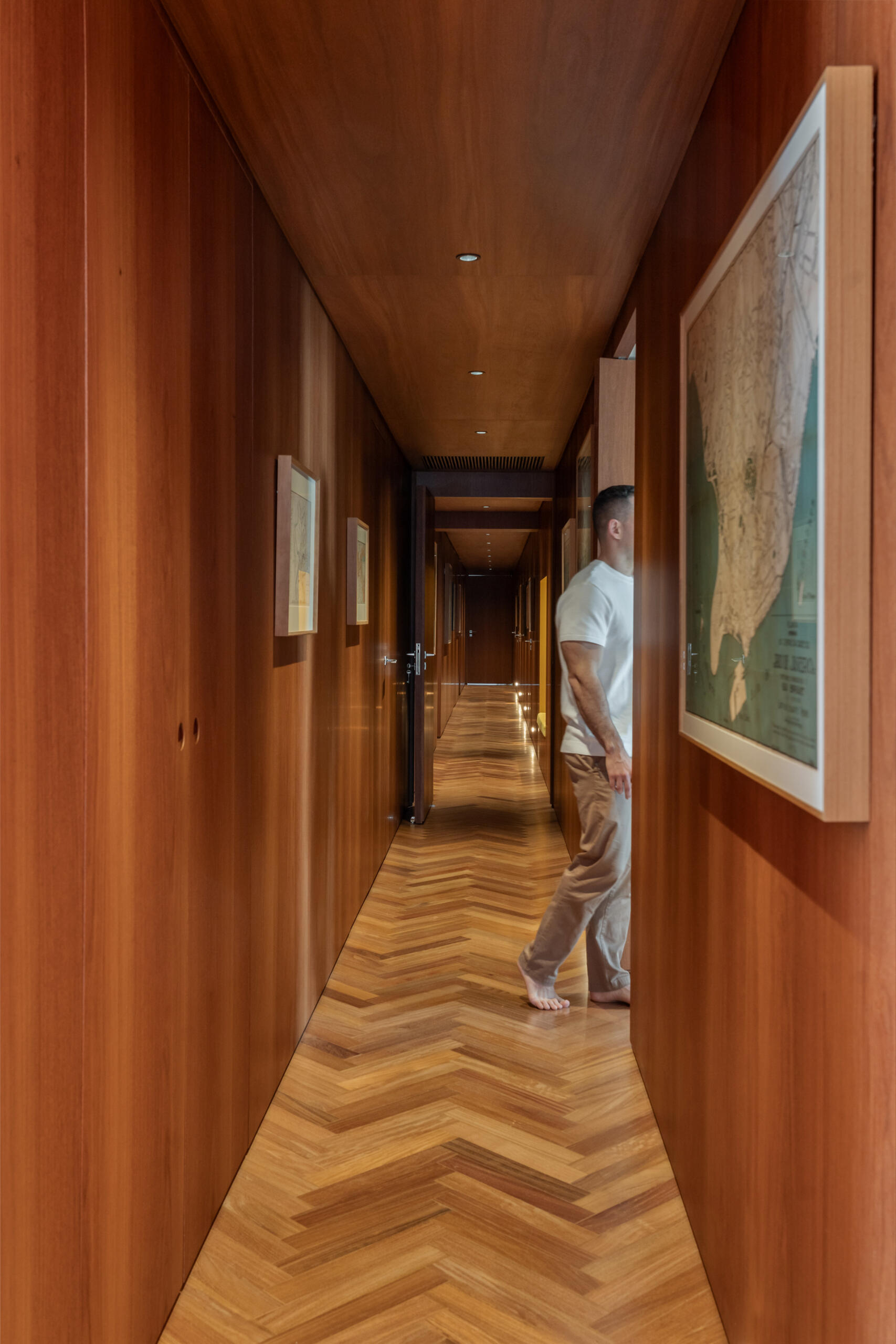 Herringbone timber, built-in benches and framed maps turn this hallway into a gallery within the home.