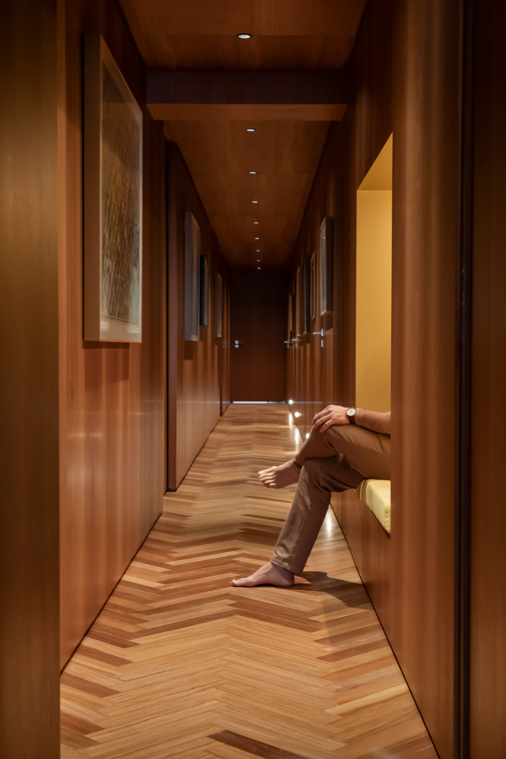 Herringbone timber, built-in benches and framed maps turn this hallway into a gallery within the home.