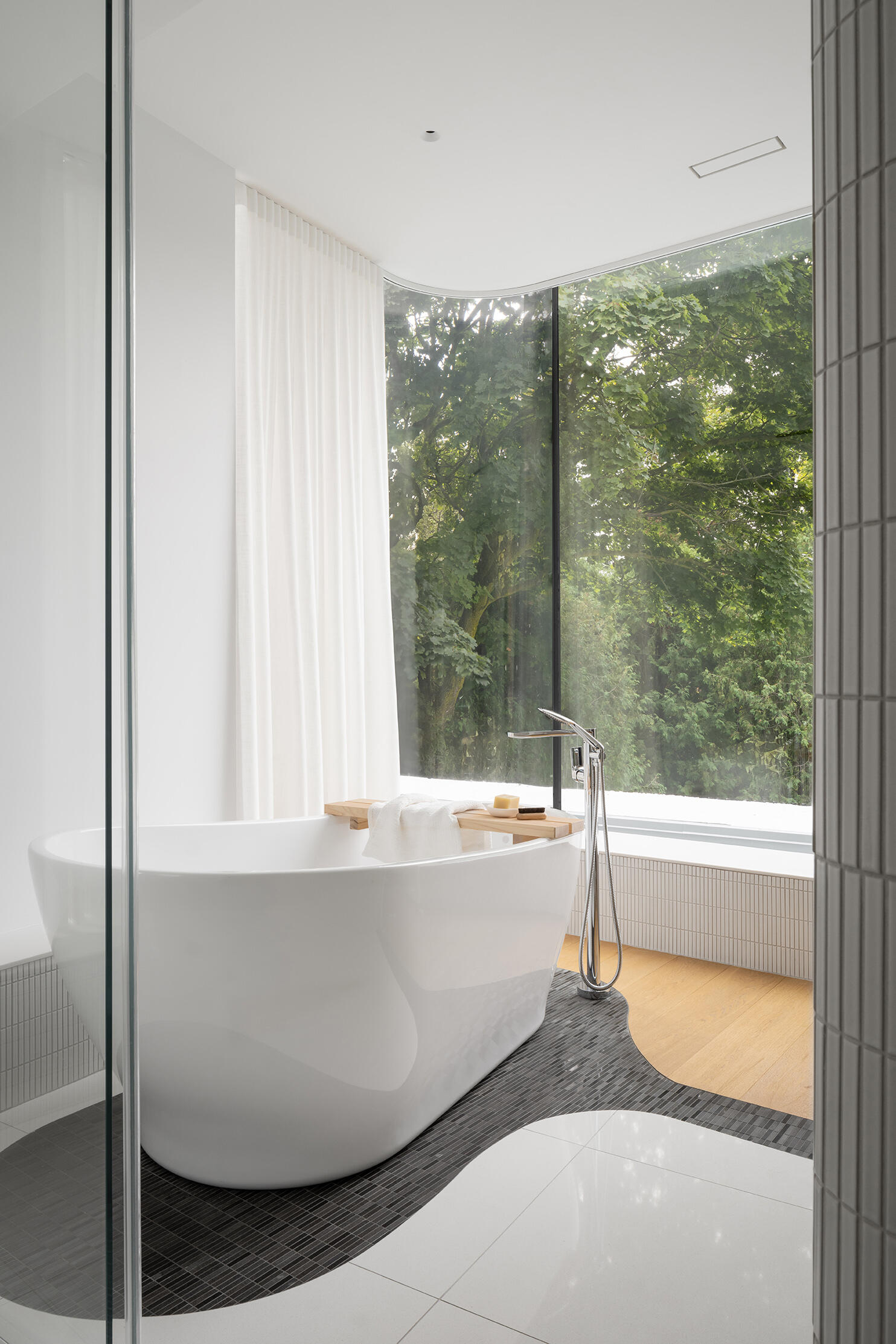 Curved marble walls, layered stone flooring, and a freestanding tub make this Toronto bathroom feel sculptural and serene.