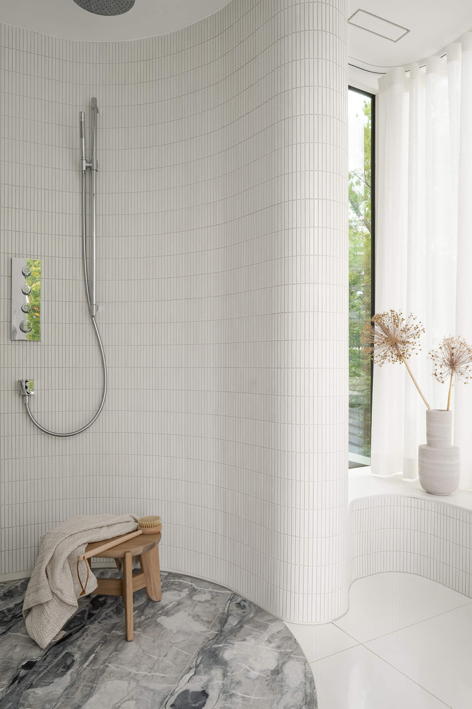 Curved marble walls, layered stone flooring, and a freestanding tub make this Toronto bathroom feel sculptural and serene.