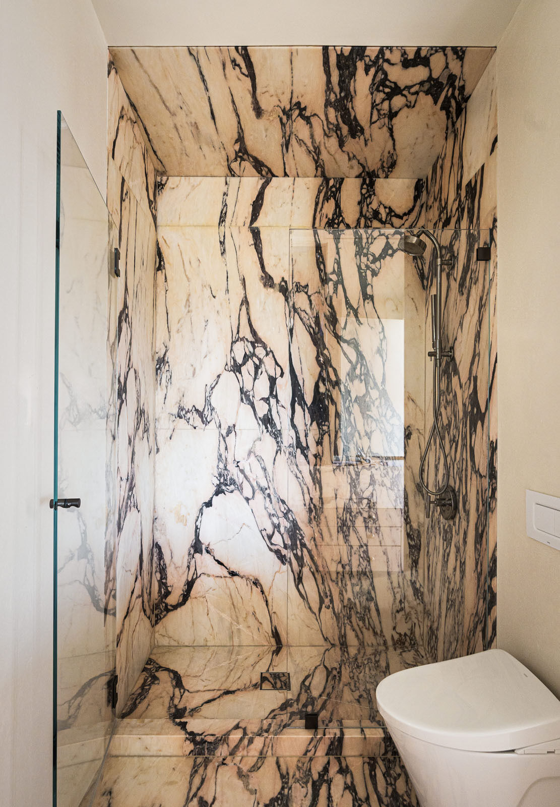 A playful bathroom finished with pink Portuguese marble adds a fun surprise inside this warm and modern Silicon Valley home.