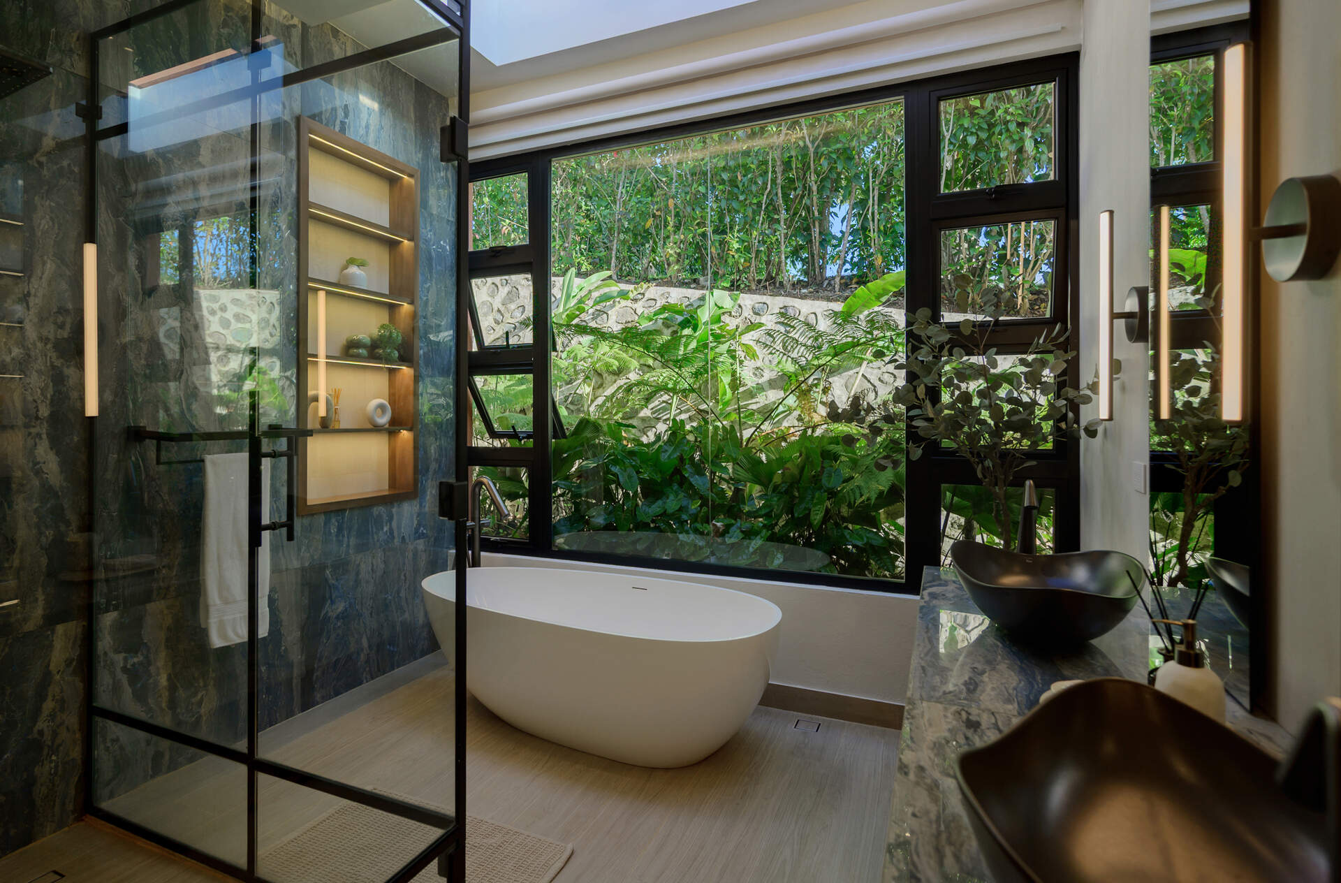 Explore a bright modern bathroom with a freestanding bathtub, built-in shelving niches, natural stone finishes and abundant daylight.
