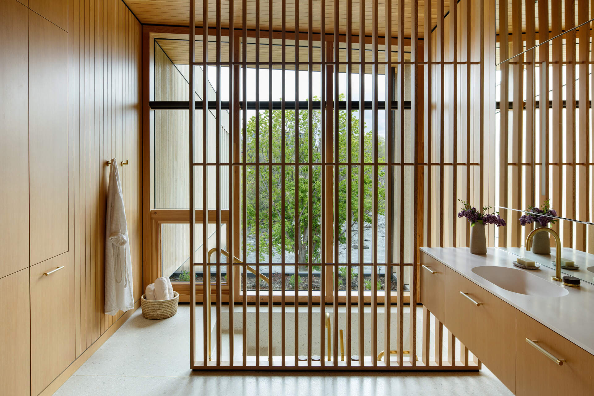 Eche un vistazo más de cerca al sereno baño principal, donde listones de madera, accesorios de latón y una bañera hundida crean un espacio lujoso inspirado en un spa.