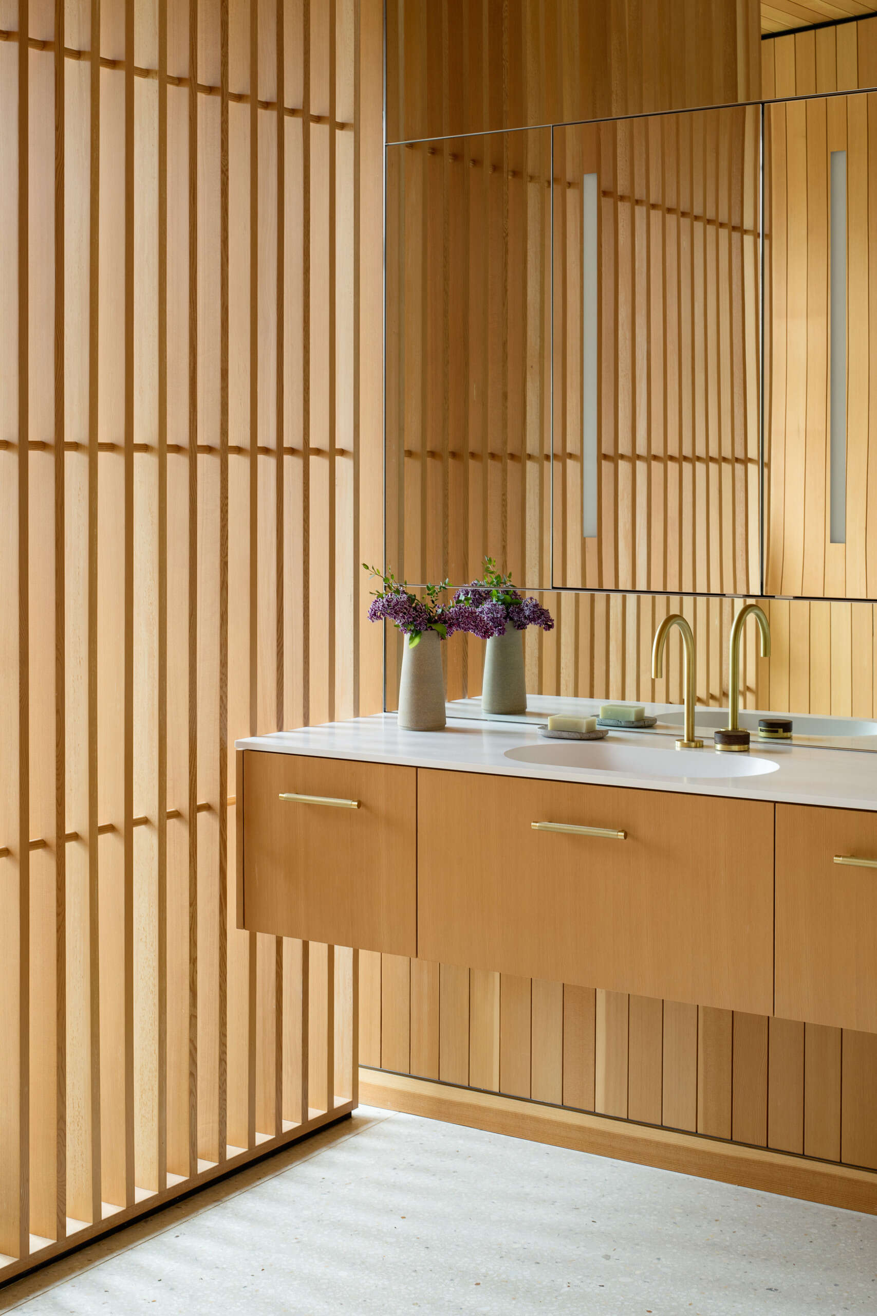 Eche un vistazo más de cerca al sereno baño principal, donde listones de madera, accesorios de latón y una bañera hundida crean un espacio lujoso inspirado en un spa.
