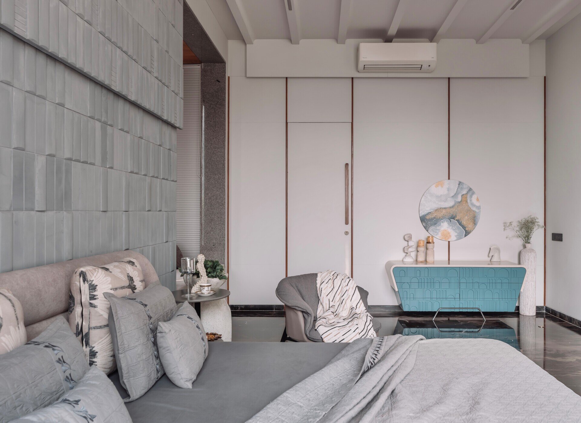 Grey textured walls, black floors and bold blue furniture give this contemporary bedroom a distinctive personality.