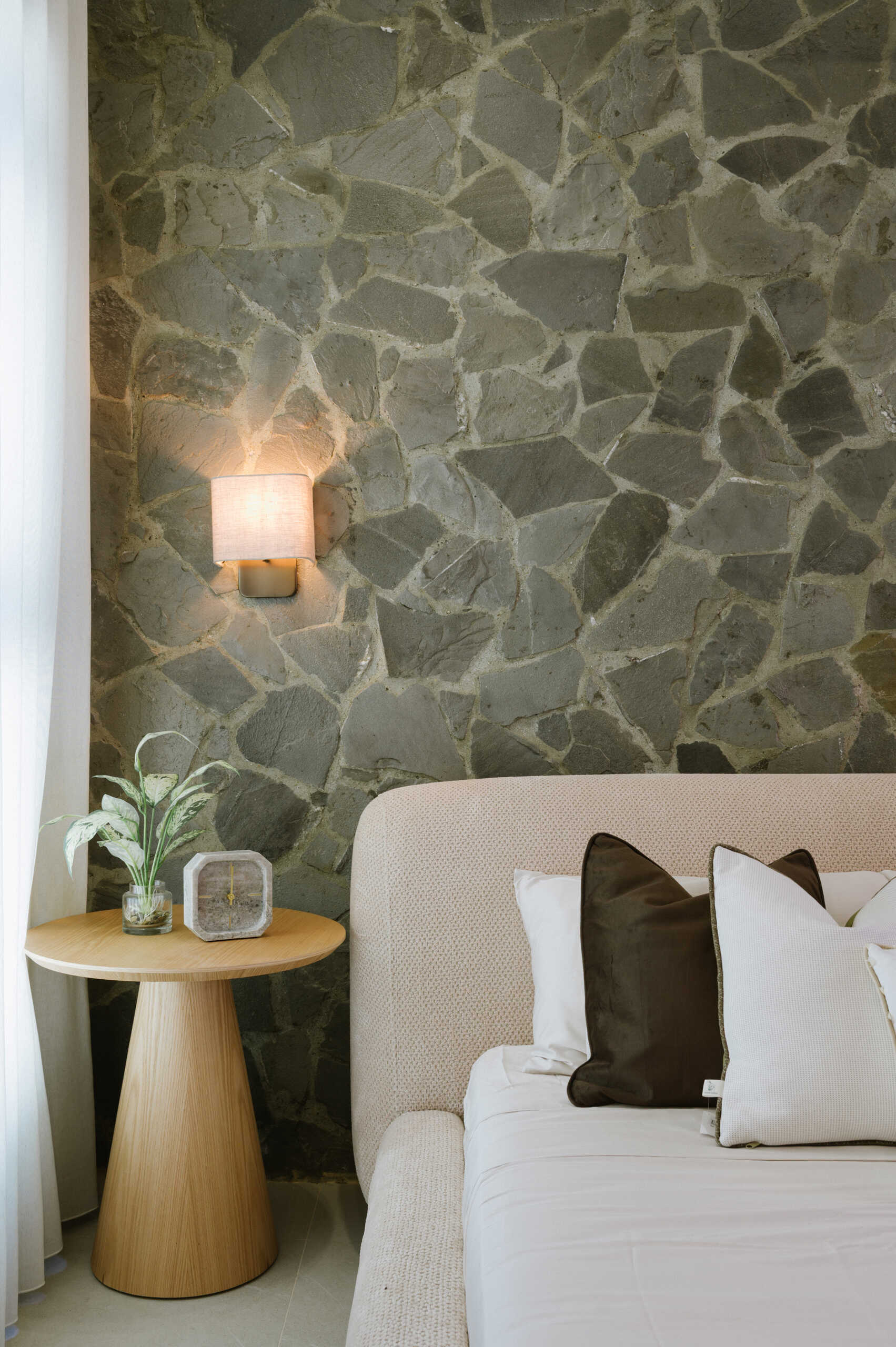 Get bedroom inspiration from this modern space featuring a natural stone feature wall, TV unit and a warm neutral colour palette.