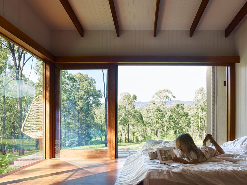 This bedroom echoes the exposed timber beams seen in the main living spaces. The beams draw attention upward, making the ceiling feel taller and giving the room an airy, spacious feel.
