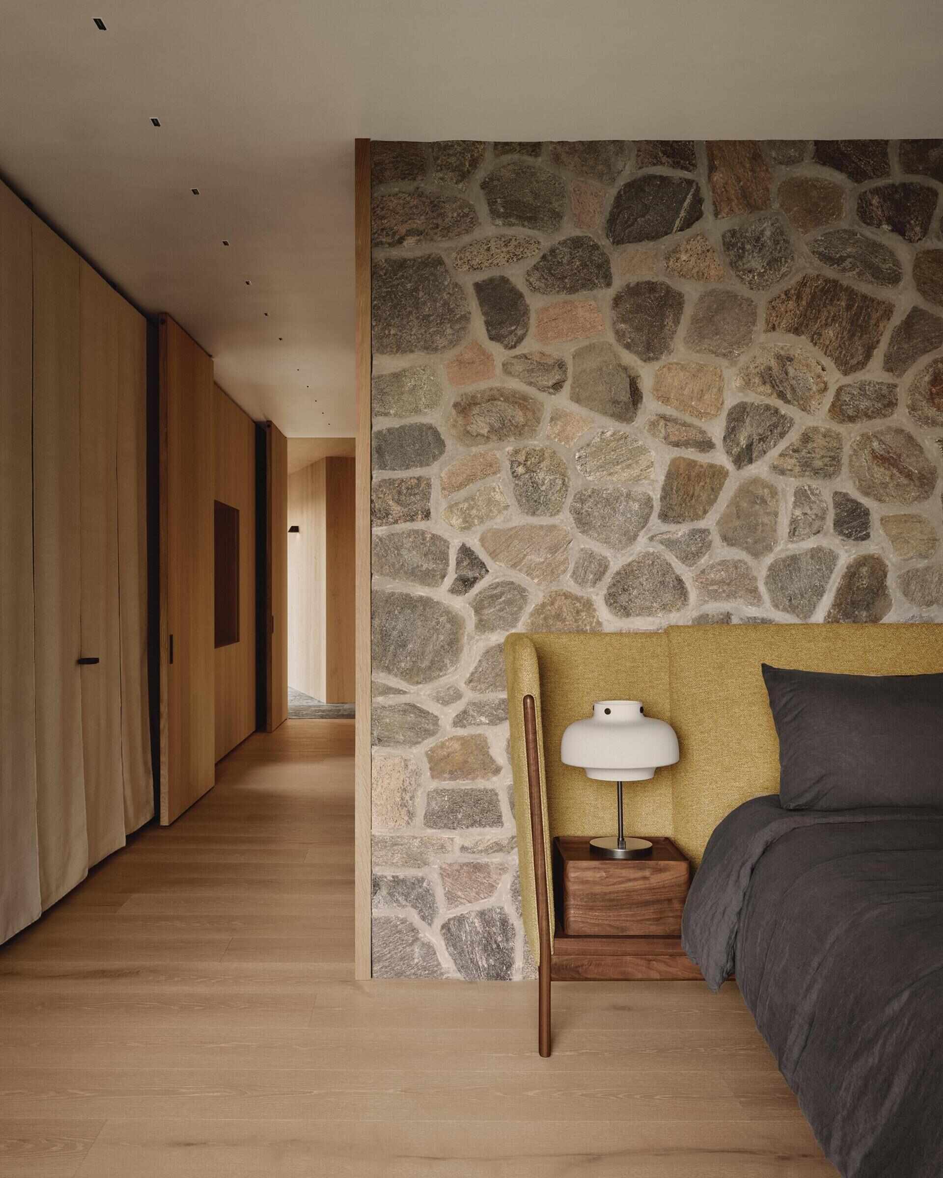Natural stone, oak and built-in storage create a warm and inviting primary bedroom.