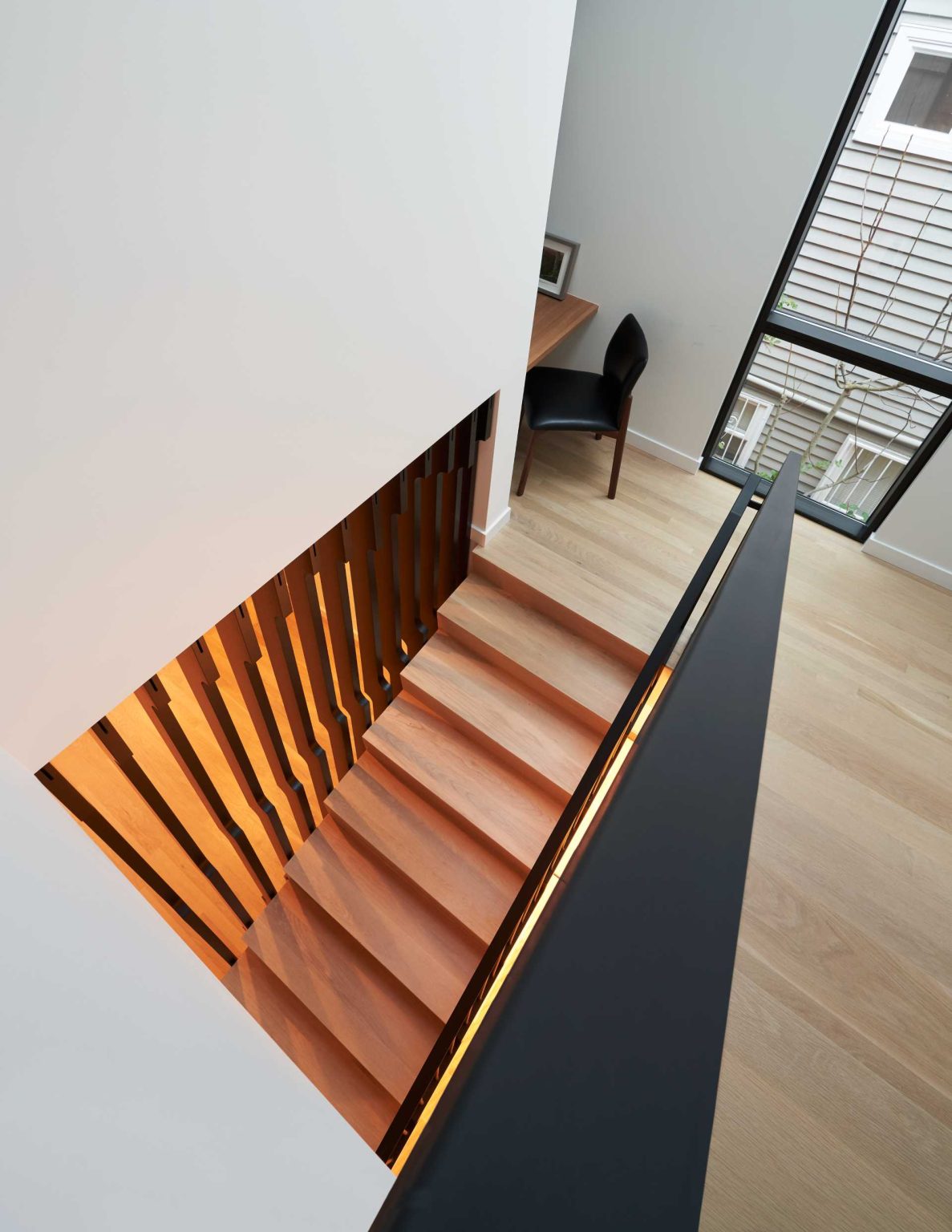 An undulating wood screen, skylight, and hidden office nook transform the staircase into one of the home's most memorable architectural features.