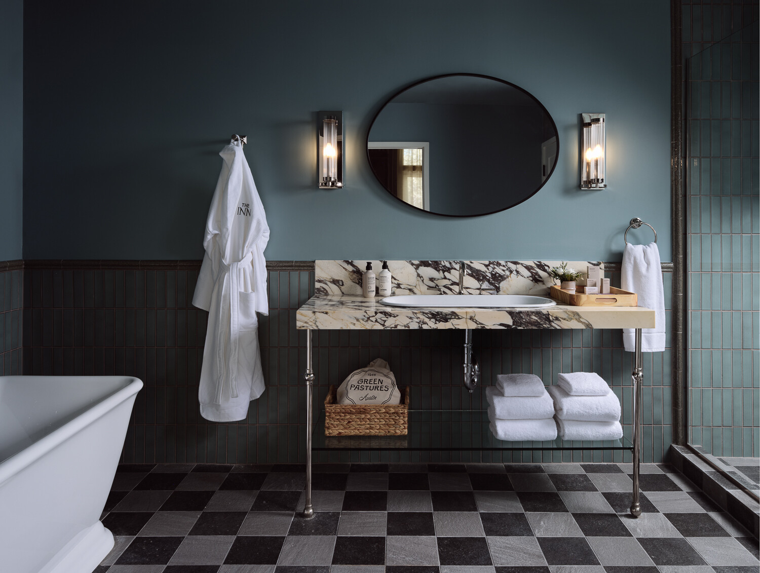 A modern bathroom with a marble vanity, vertical deep blue tiles covering the walls, and checkerboard flooring.