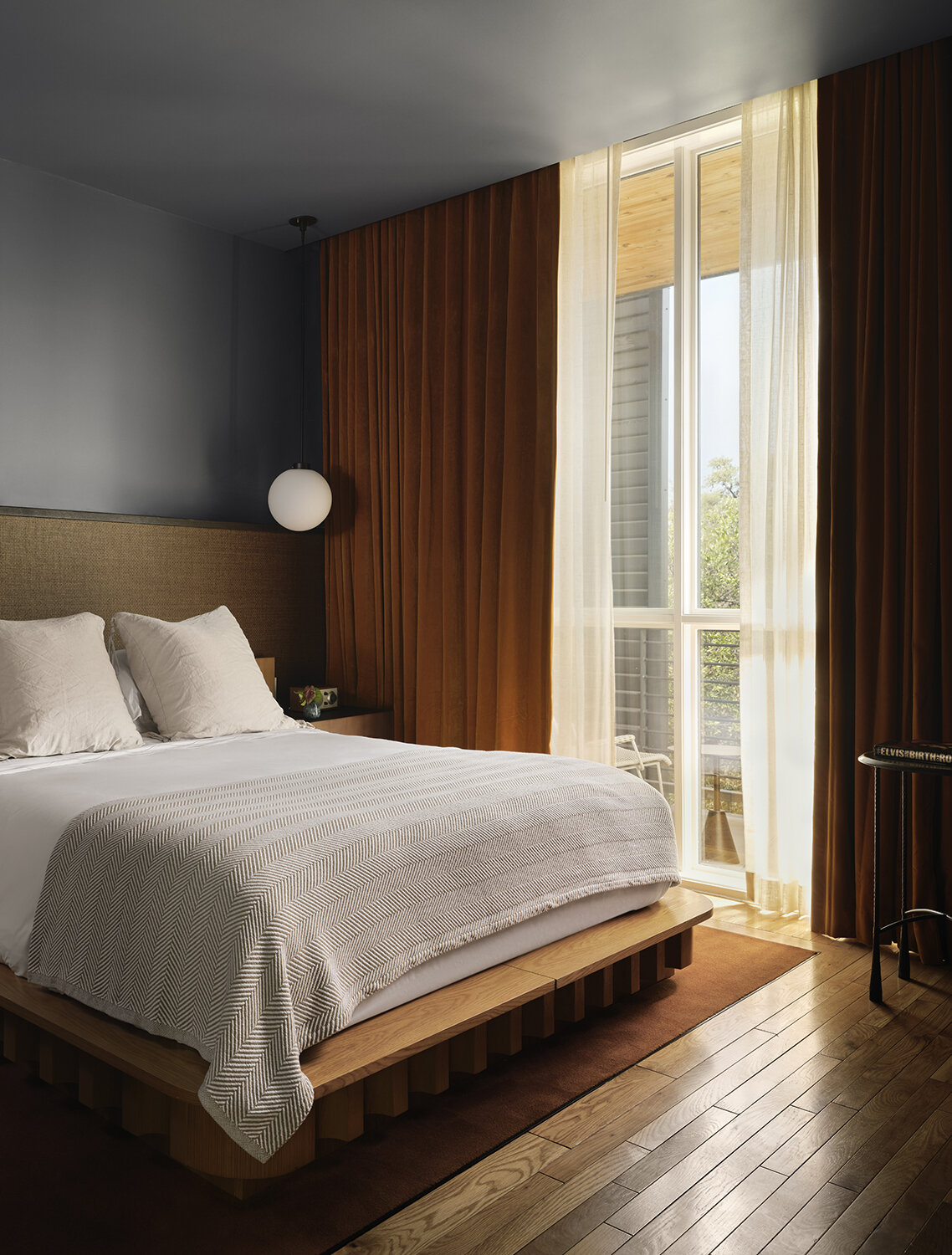 A modern hotel room with dusty blue walls and rattan accents.